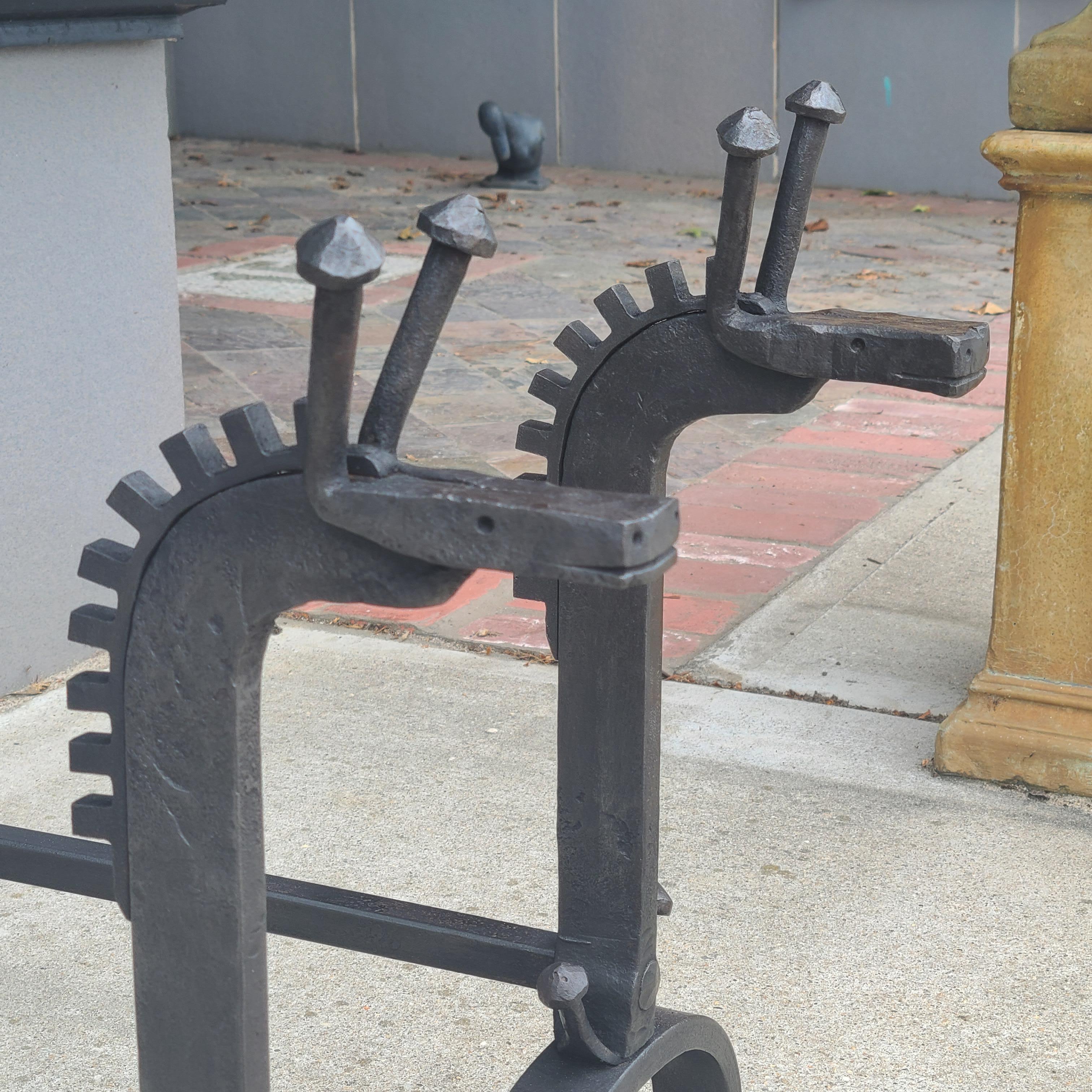 A whimsical pair of hand forged andirons made to look like a stylized giraffe, they are a nice balance of folk art, craft and modern design. A truly unique and one of a kind set of andirons.