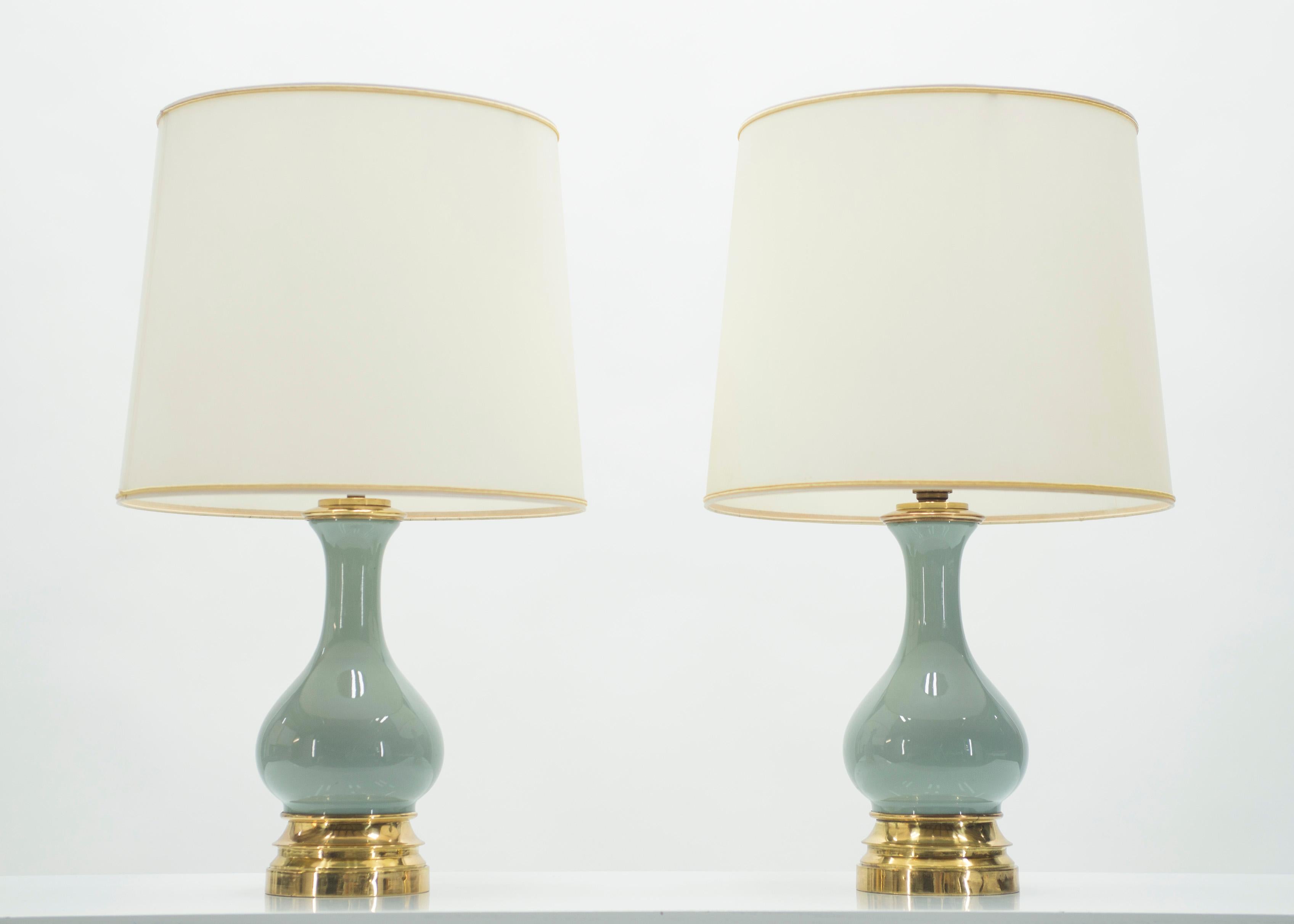 All understated luxury, this pair of 1950s French bedside lamps boast the exquisite craftsmanship characteristic of midcentury French ceramics. Featuring elegantly rounded curves with distinguished brass feet, the ceramic subtly captures the light