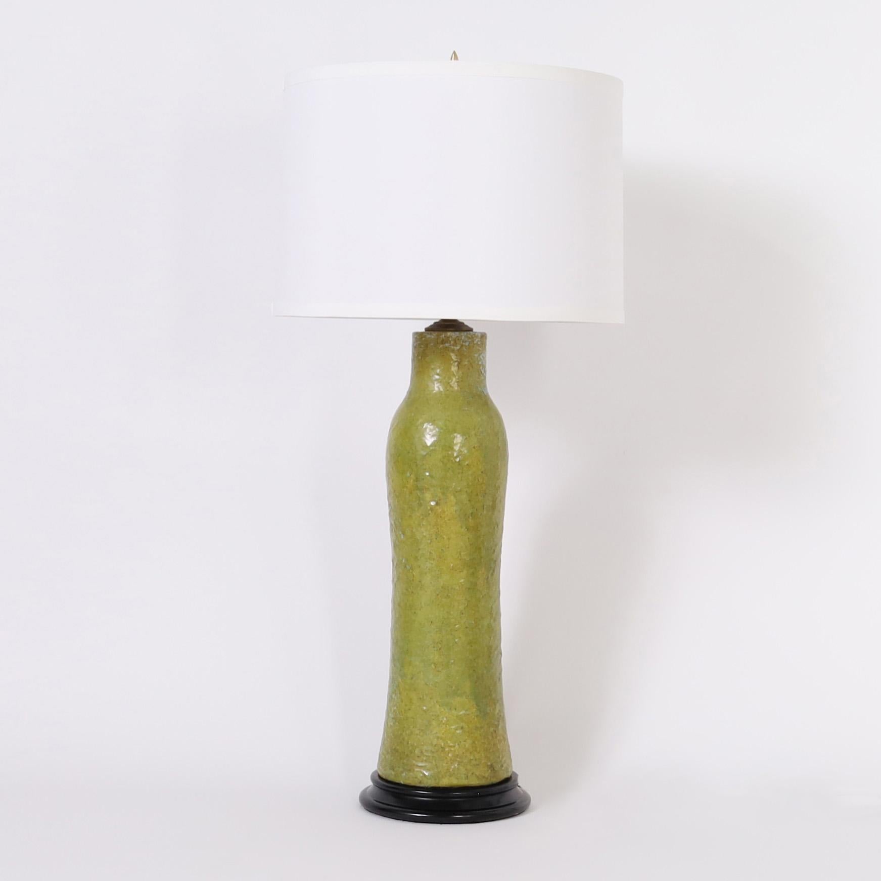 Chic pair of vintage table lamps crafted in terra cotta in a sophisticated sculptural form with a thick granular green glaze. Presented on turned wood bases.