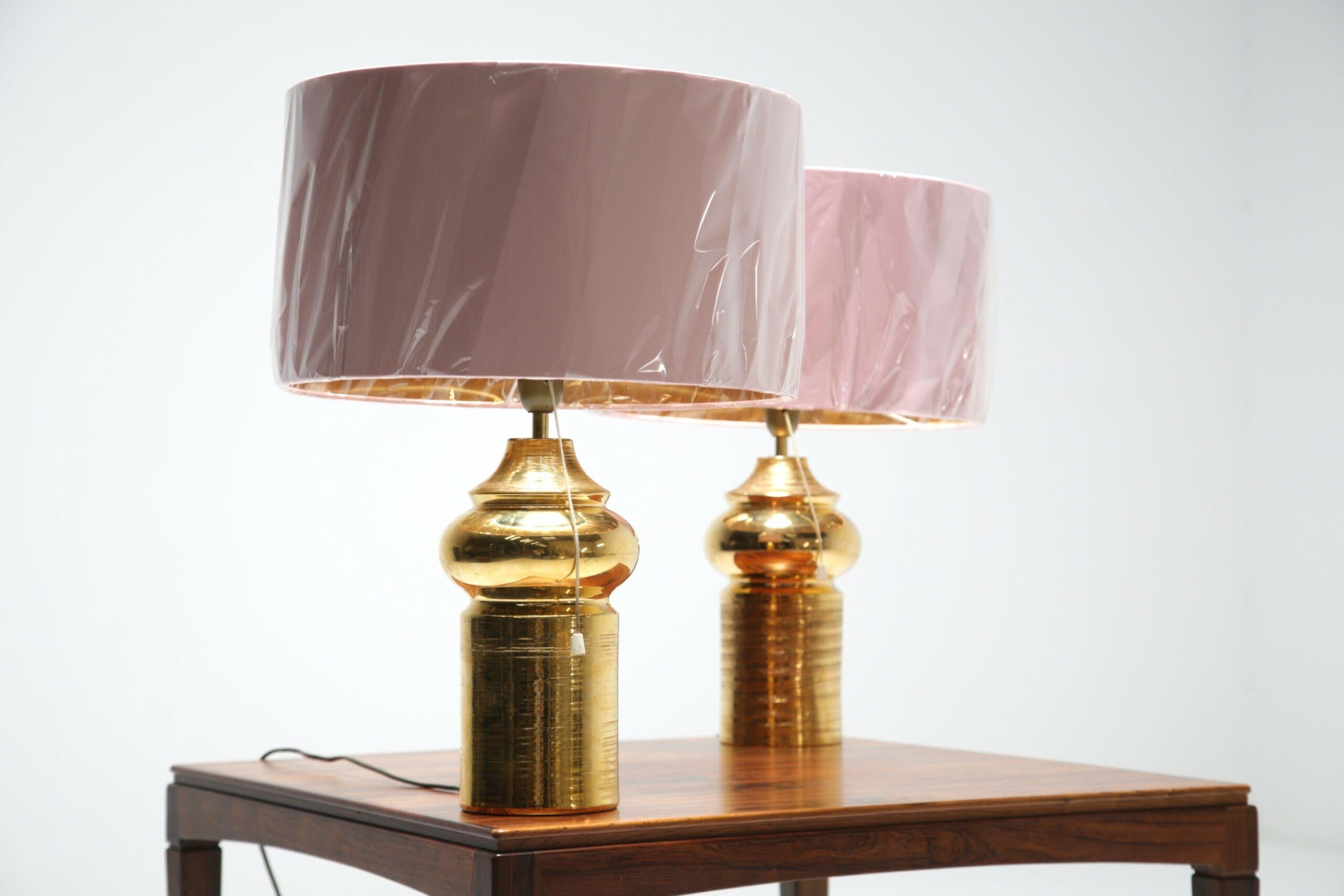 Coppia di splendide lampade da tavolo in ceramica dorata di Bitossi per Bergboms, Svezia, circa 1970. Abbiamo abbinato queste lampade da tavolo con paralumi contemporanei a scopo fotografico. Il design elegante e senza tempo rende omaggio al genio