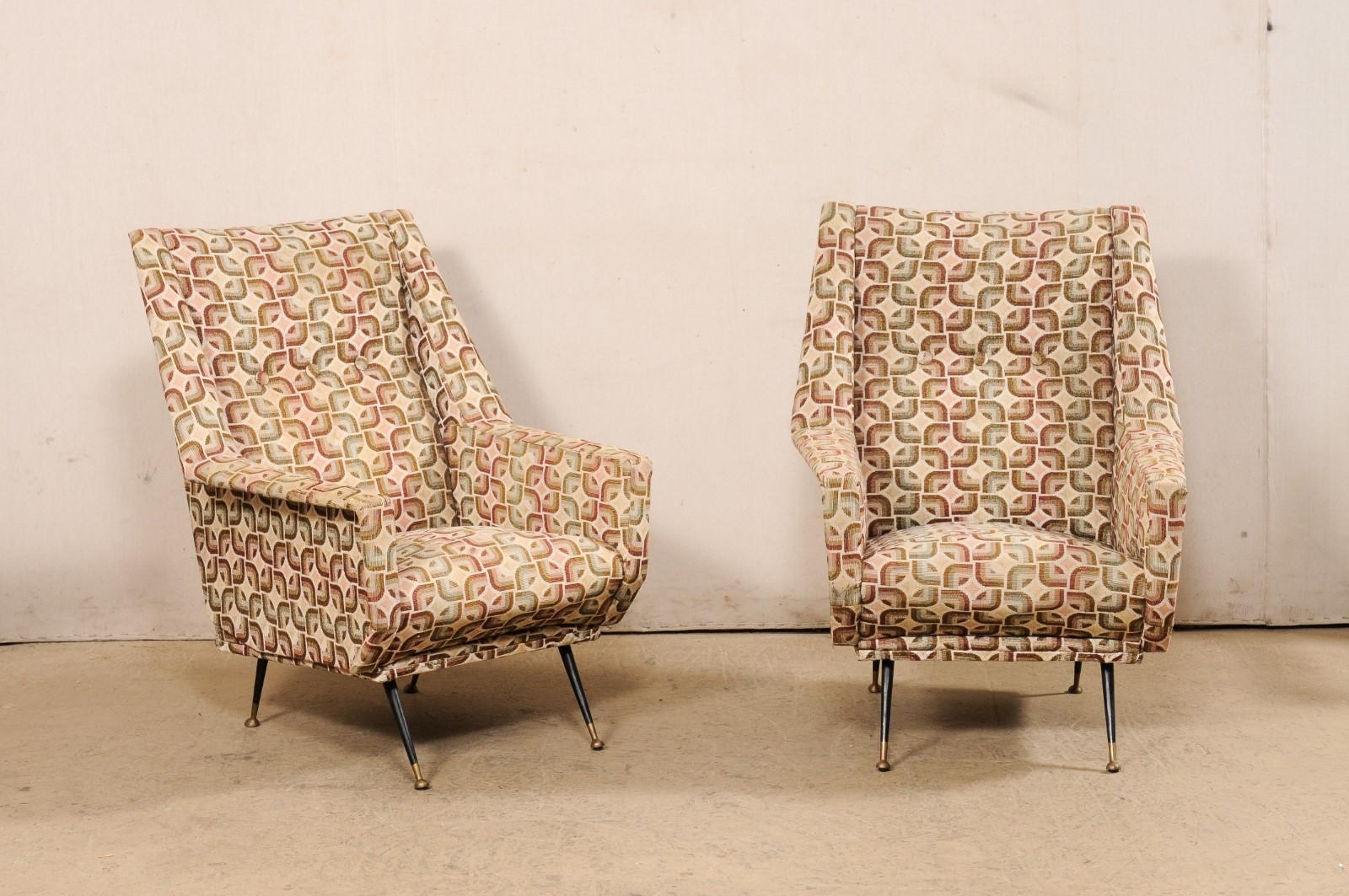 An Italian pair of upholstered wingback armchairs from the mid-20th century. These vintage chairs from Italy have been designed with midcentury styling with upholstered rectangular backs framed within outwardly folded arms that are angular and
