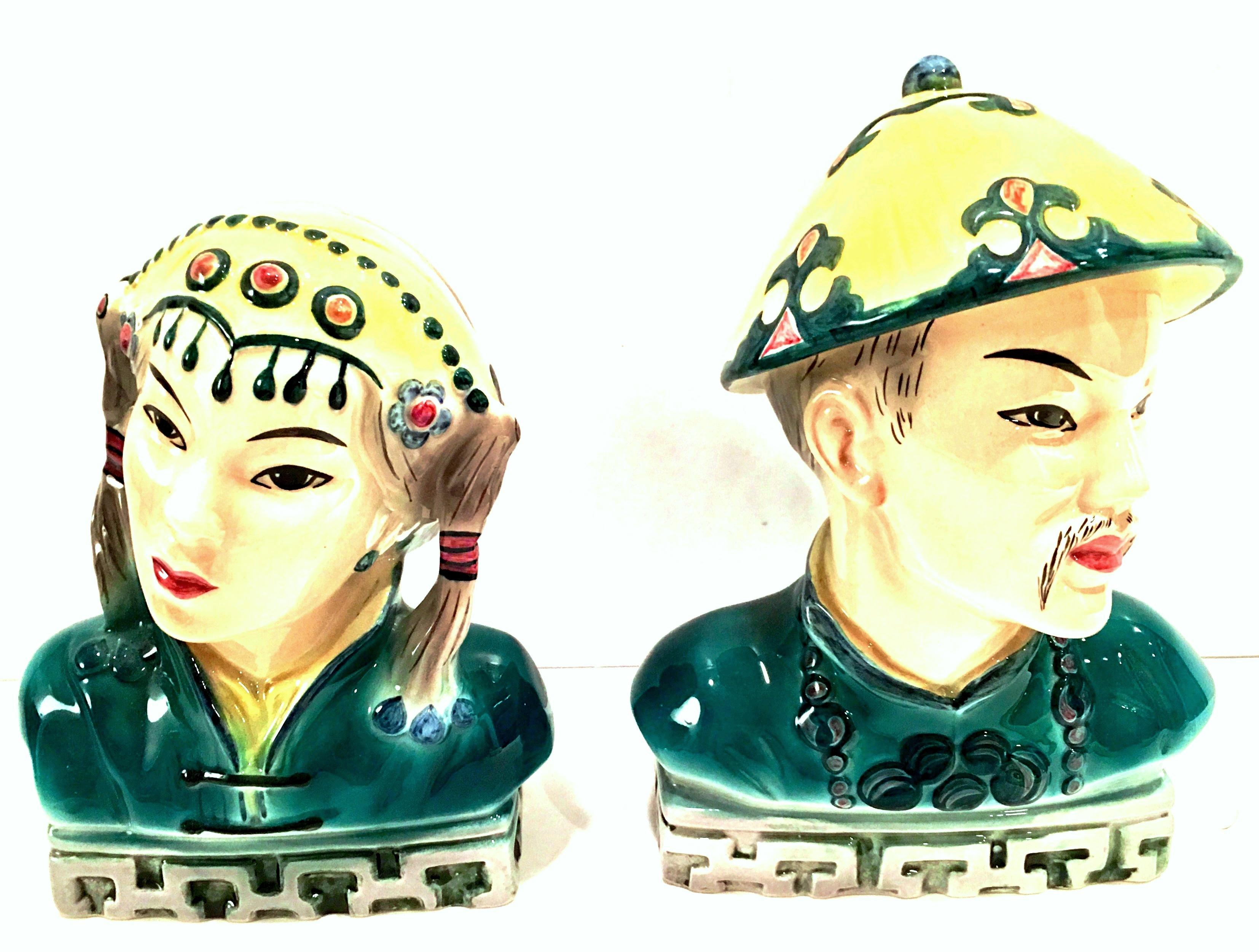 Mid-20th century pair of Japanese hand painted porcelain Asian couple sculptures by Goldscheider-Japan. Finely executed in great detail with a high gloss hand painted teal, yellow, grey, white, black and red details. Features a Greek key motif at
