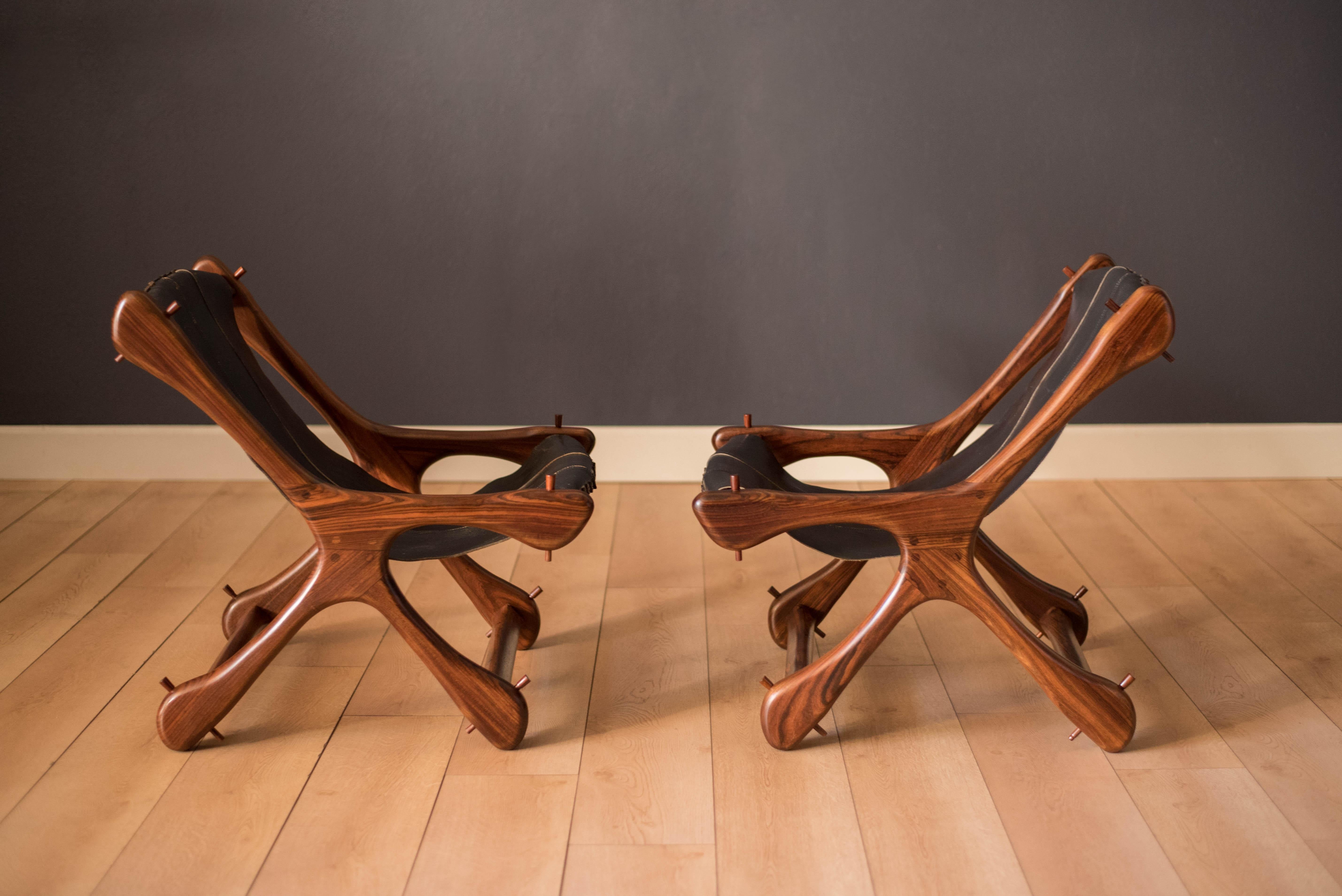 Mid-Century Modern pair of sling chairs designed by Don Shoemaker in cocobolo rosewood manufactured by Senal S.A., Mexico. This sculptural pair features flowing rosewood grains and contrasting joinery. Displays well from all angles and retains the