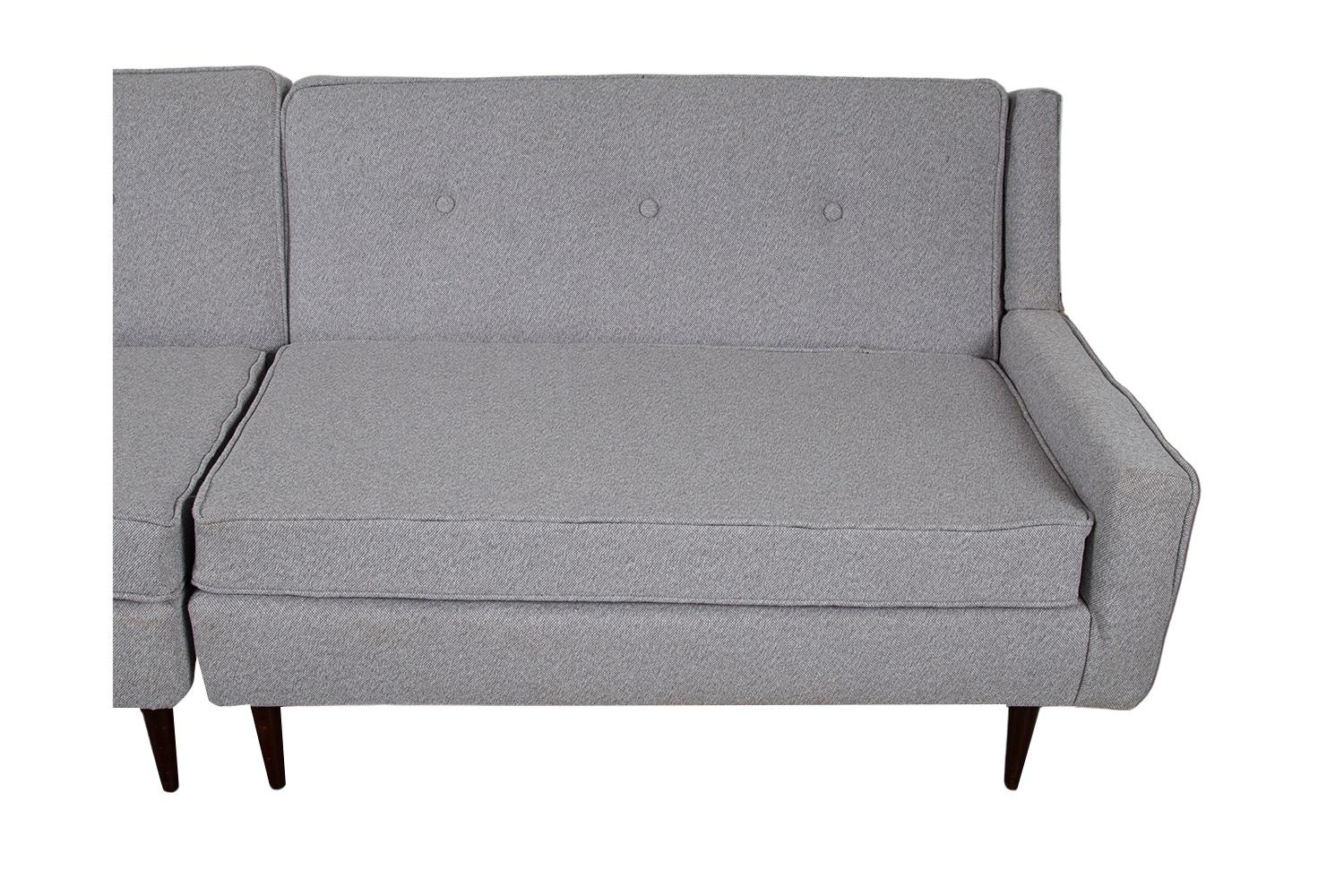 A beautiful pair of mid-century modern loveseat/sofas, in new upholstery fabric and high-density foam. Each with an appealing design that allows them to be positioned either as a pair of loveseats, as a sectional with a table in the corner between