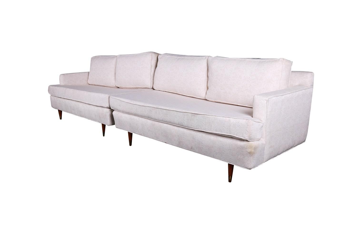 A beautiful pair of Mid-Century Modern sofas each with an appealing design that allows them to be positioned either as a pair of loveseats, as a sectional with a table in the corner between them, or as a single long sofa depending on your