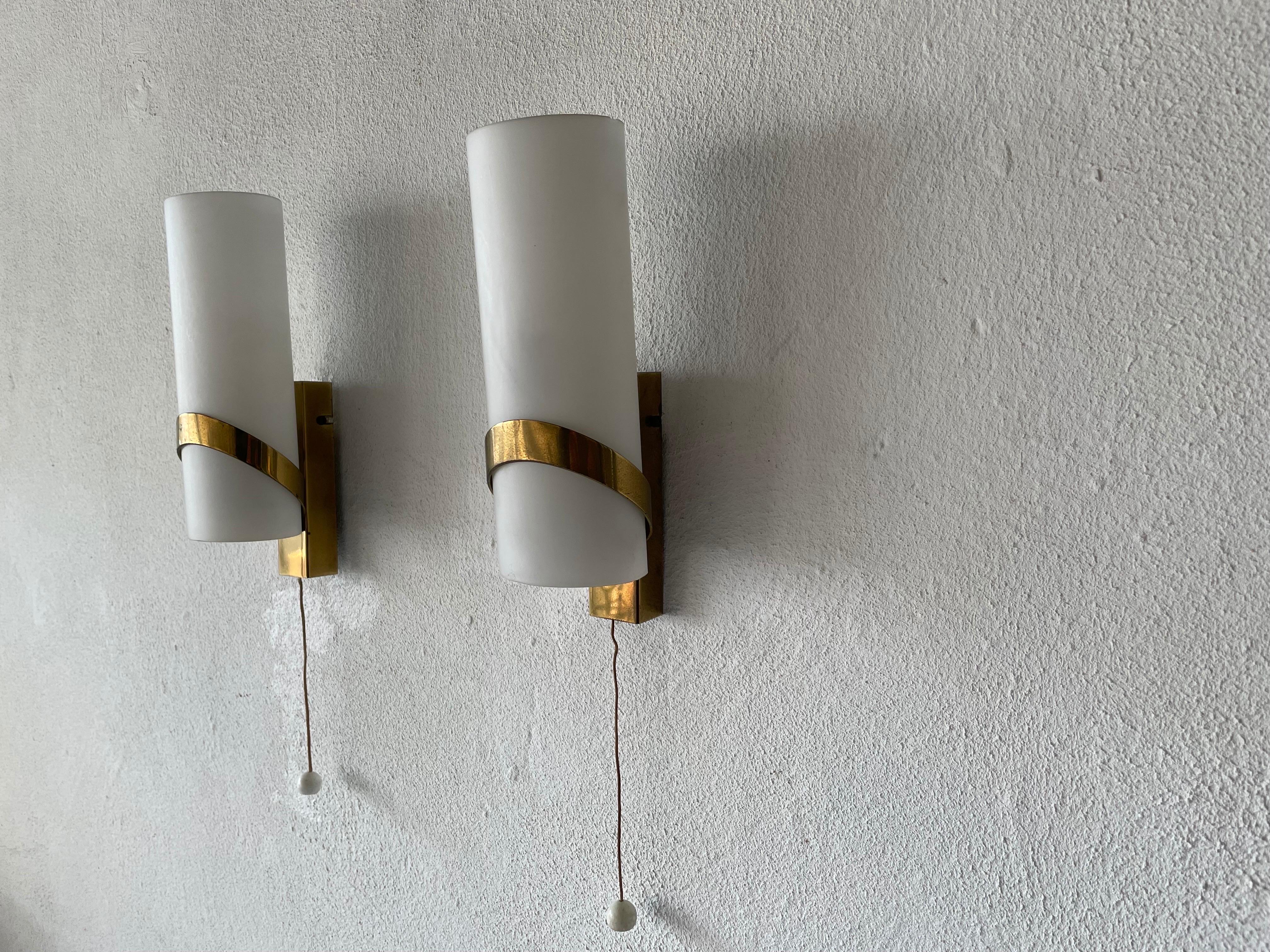 Mid-century pair of sconces by Stilnovo, 1950s, Italy

Very elegant and Minimalist wall lamps

Brushed satin glass diffusers and brass.

Lamp is in very good condition.
These lamps works with E14 standard light bulbs. 
Wired and suitable to
