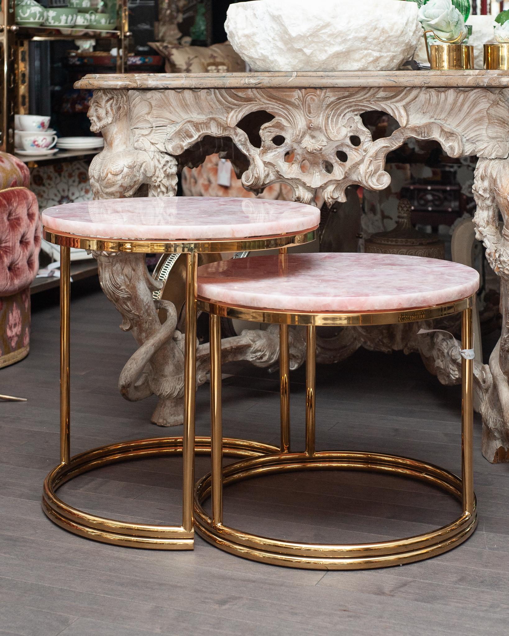 A stunning pair of mid century rose quartz and polished brass nesting tables. Measuring 19.5” diameter by 21” height for higher table, and 19.5 diameter by 17” high on lower table. Rose quartz, the stone of universal love, will bring peace and
