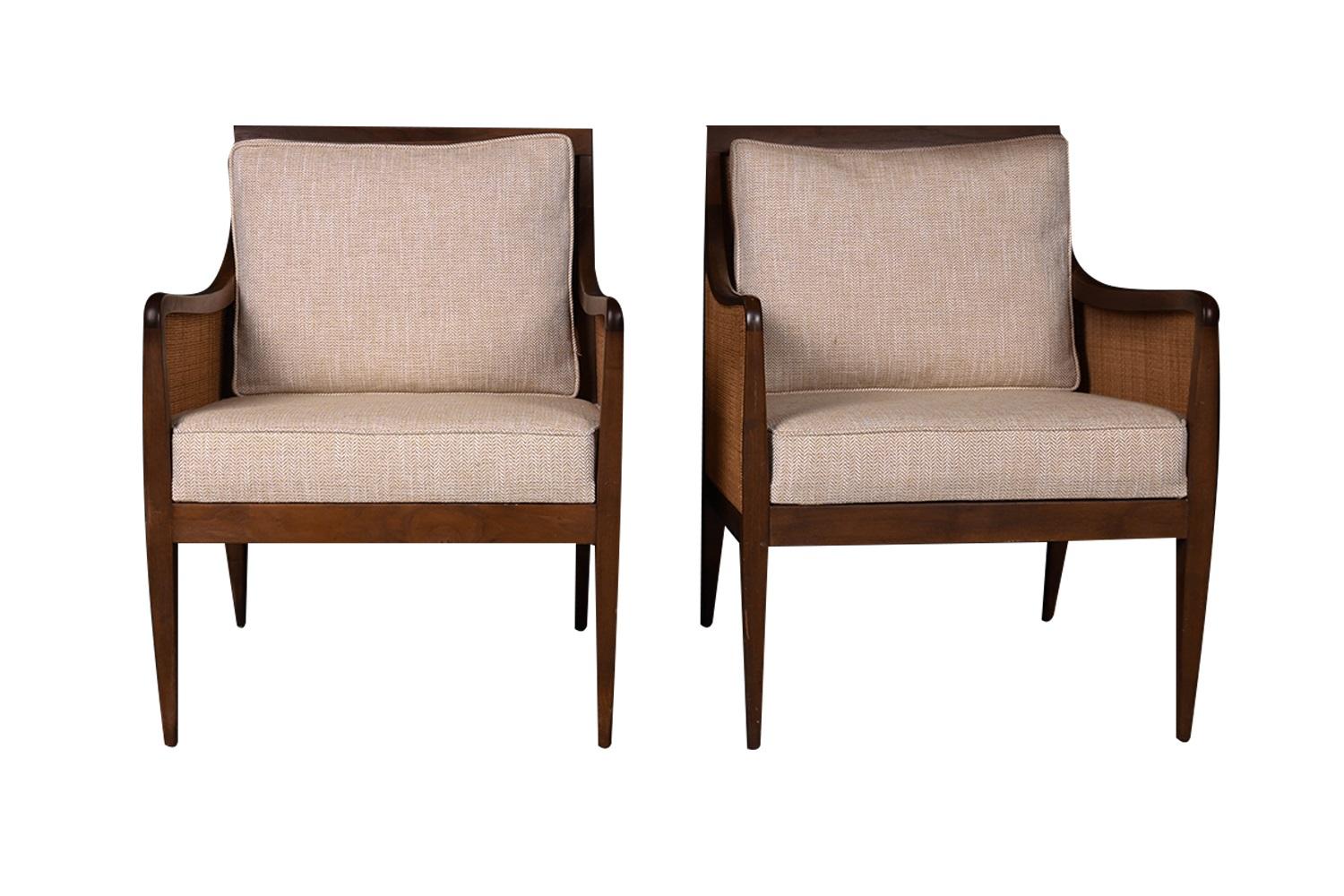 An extraordinary pair of walnut and cane newly upholstered lounge chairs designed by the distinguished architect Kipp Stewart for Directional circa 1950's, part of Directional's Country Villa collection. This elegant pair of newly upholstered