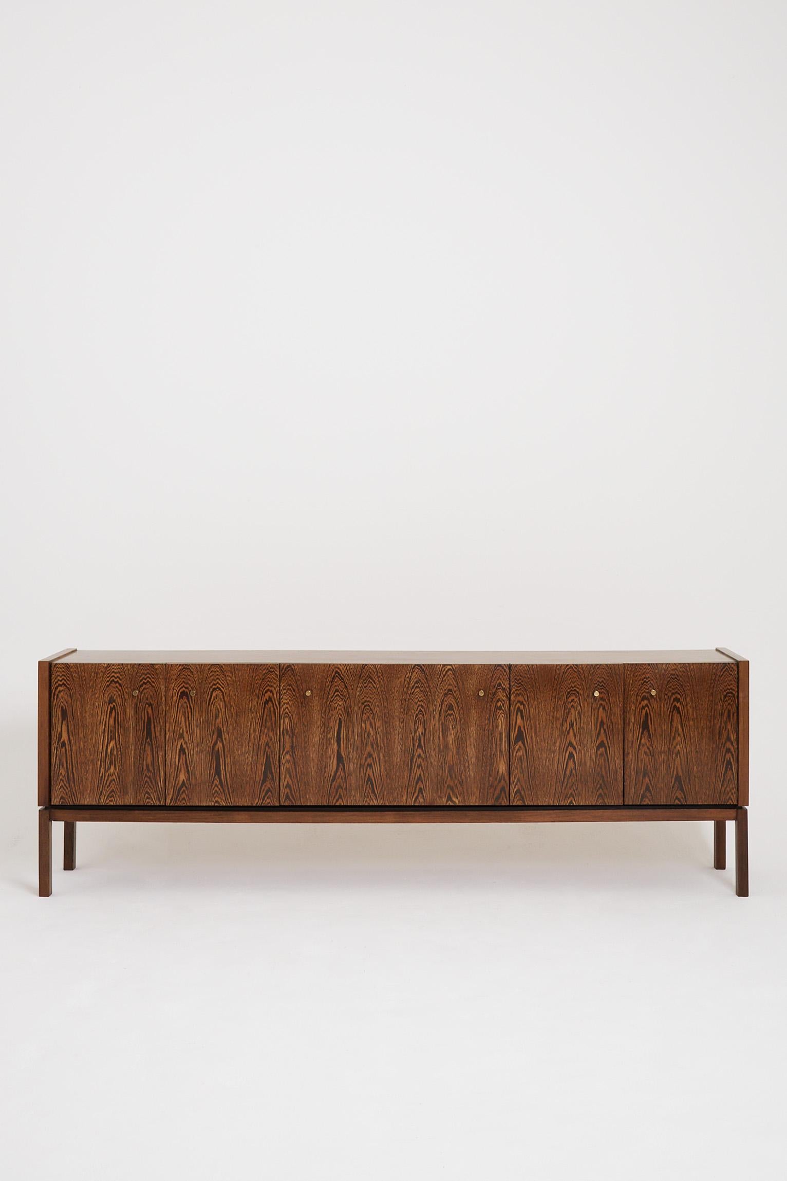 A long panga-panga wood, brass mounted long sideboard, with two double doors and a central cabinet opening with an abattant.
France, third quarter of the 20th Century.