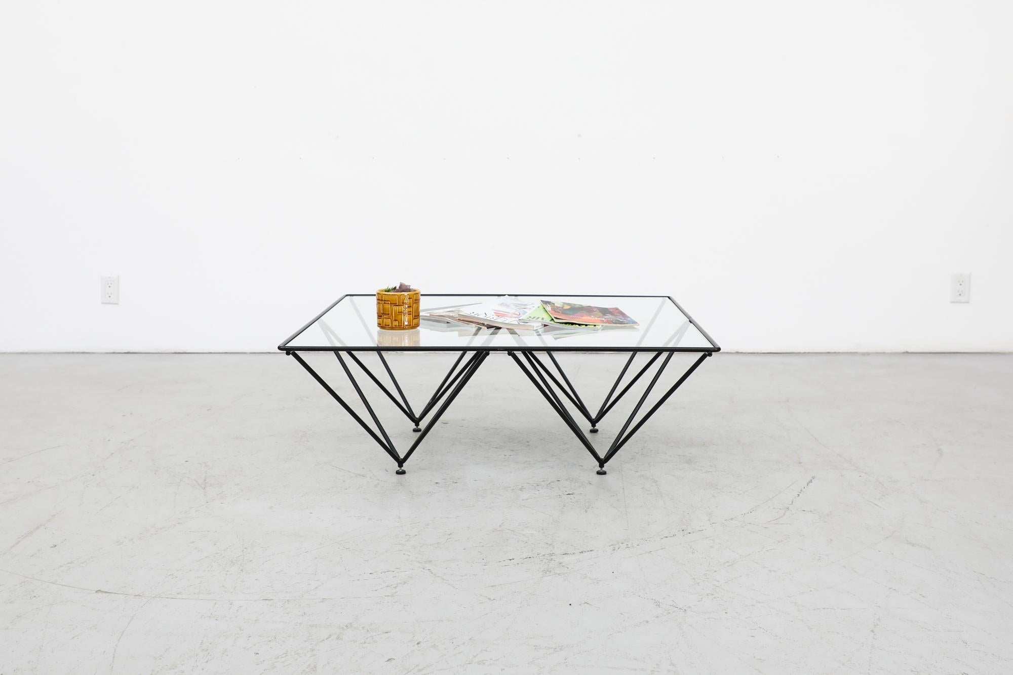 Italian Mid-Century square glass coffee table with black architectural pyramid frame. Designed in the style of the 'Alanda' table by Paolo Piva. The frame is black enameled metal with four upside down pyramids and adjustable feet, the glass is
