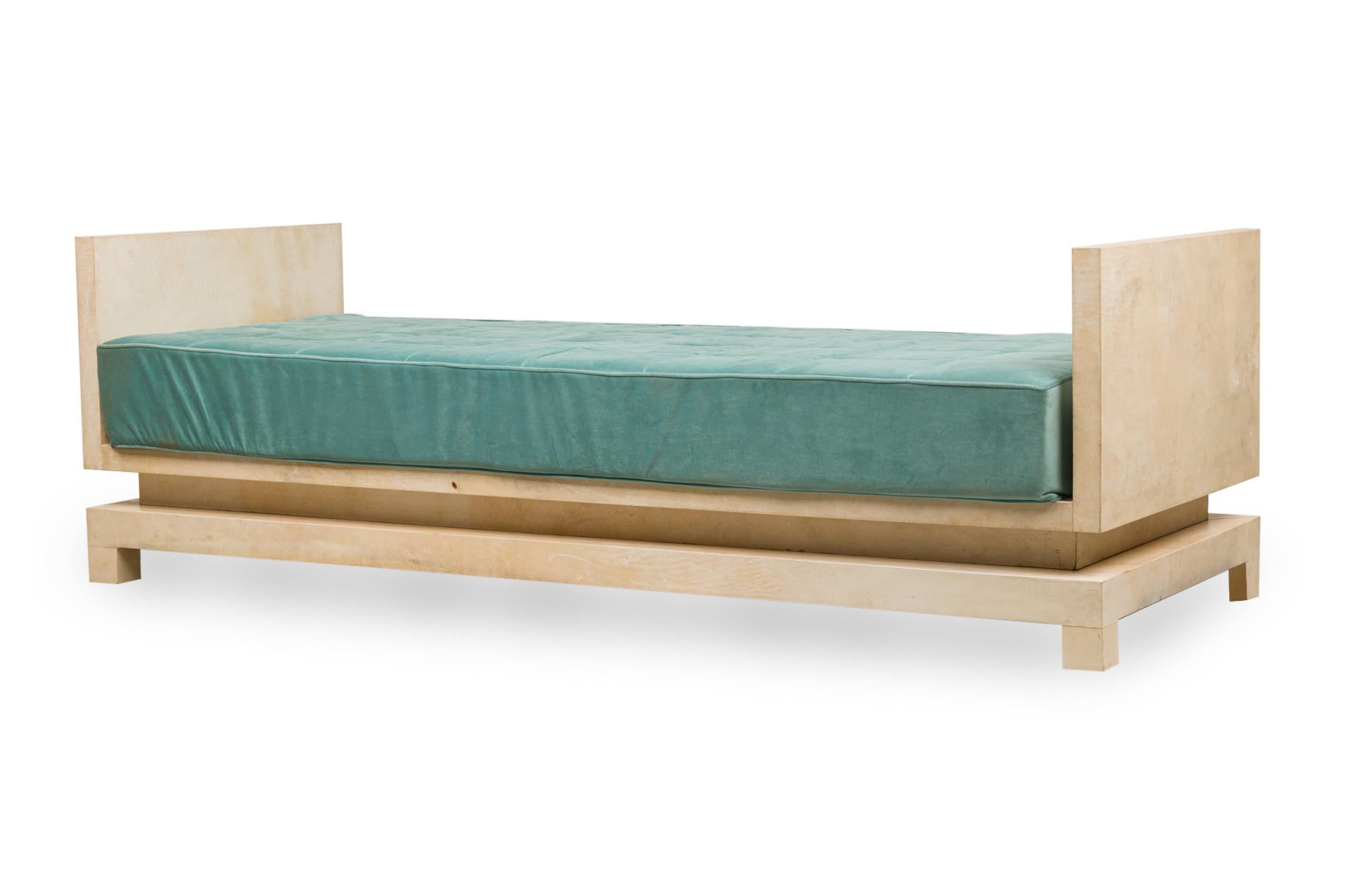Midcentury American parchment-covered rectangular daybed in a modern geometric style on a raised platform with an upholstered, tufted seat cushion in a light turquoise fabric, resting on 4 block legs. (In the manner of Samuel Marx).