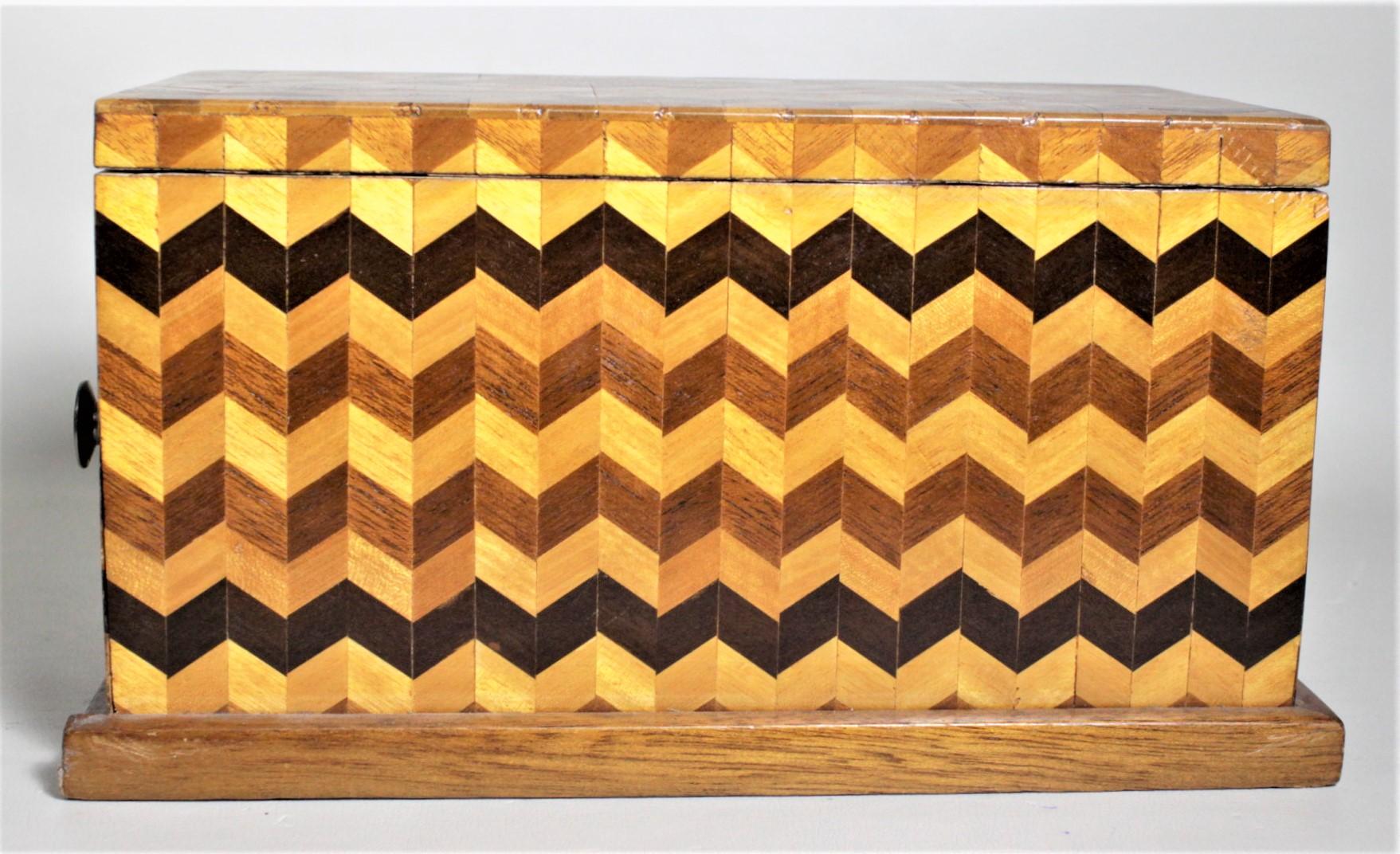 This Mid-Century Modern era parquetry wooden jewelry box was made in the United States in approximately 1955 in a cubist style. The box is done in a series of woods with various stains geometrically cut and applied to the outside of the box in a