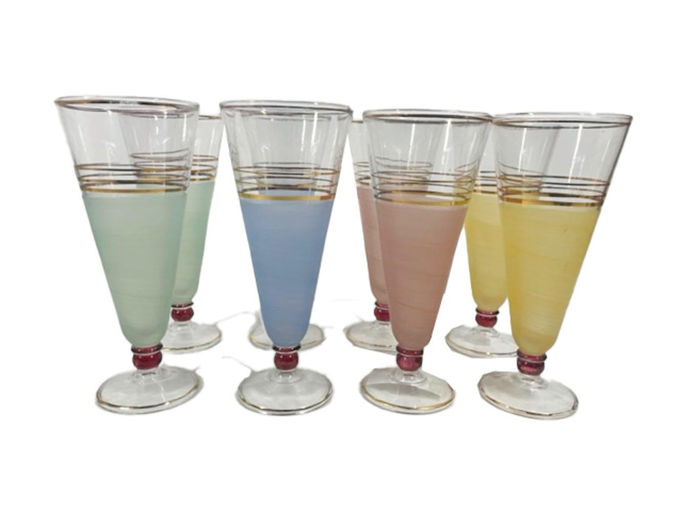 Eight Mid-Century Modern pilsner glasses of taper form, color-frosted lower two thirds below clear tops with 22k gold accent, supported on a cranberry flashed ball above a raised dome foot. The set is comprised of two each, pink, yellow, green and