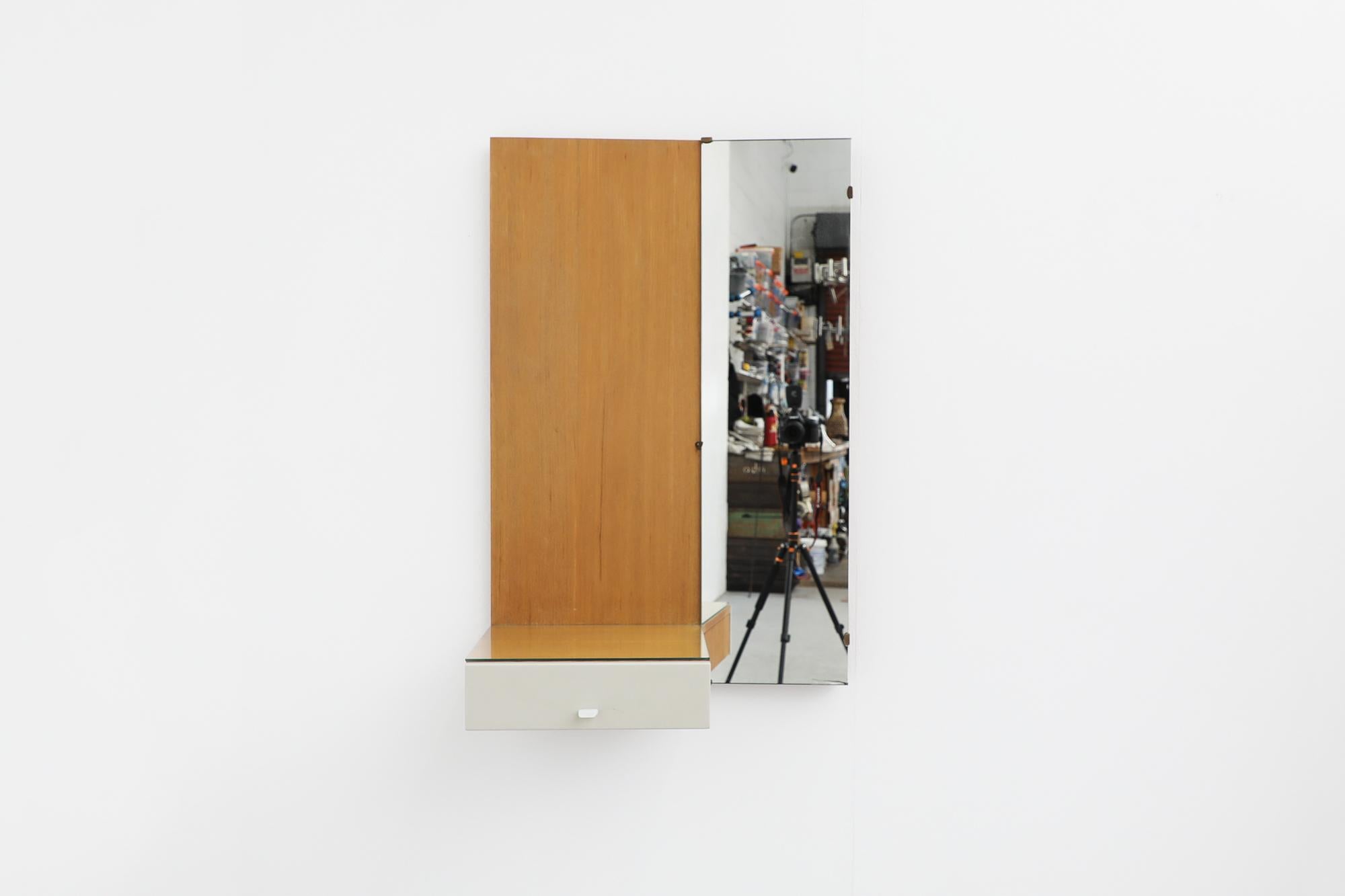 Mid-Century wall mounted mirror with white stained wood drawer and beech wood frame by Pastoe. This vintage Cees Braakman attributed wall mirror has a 13