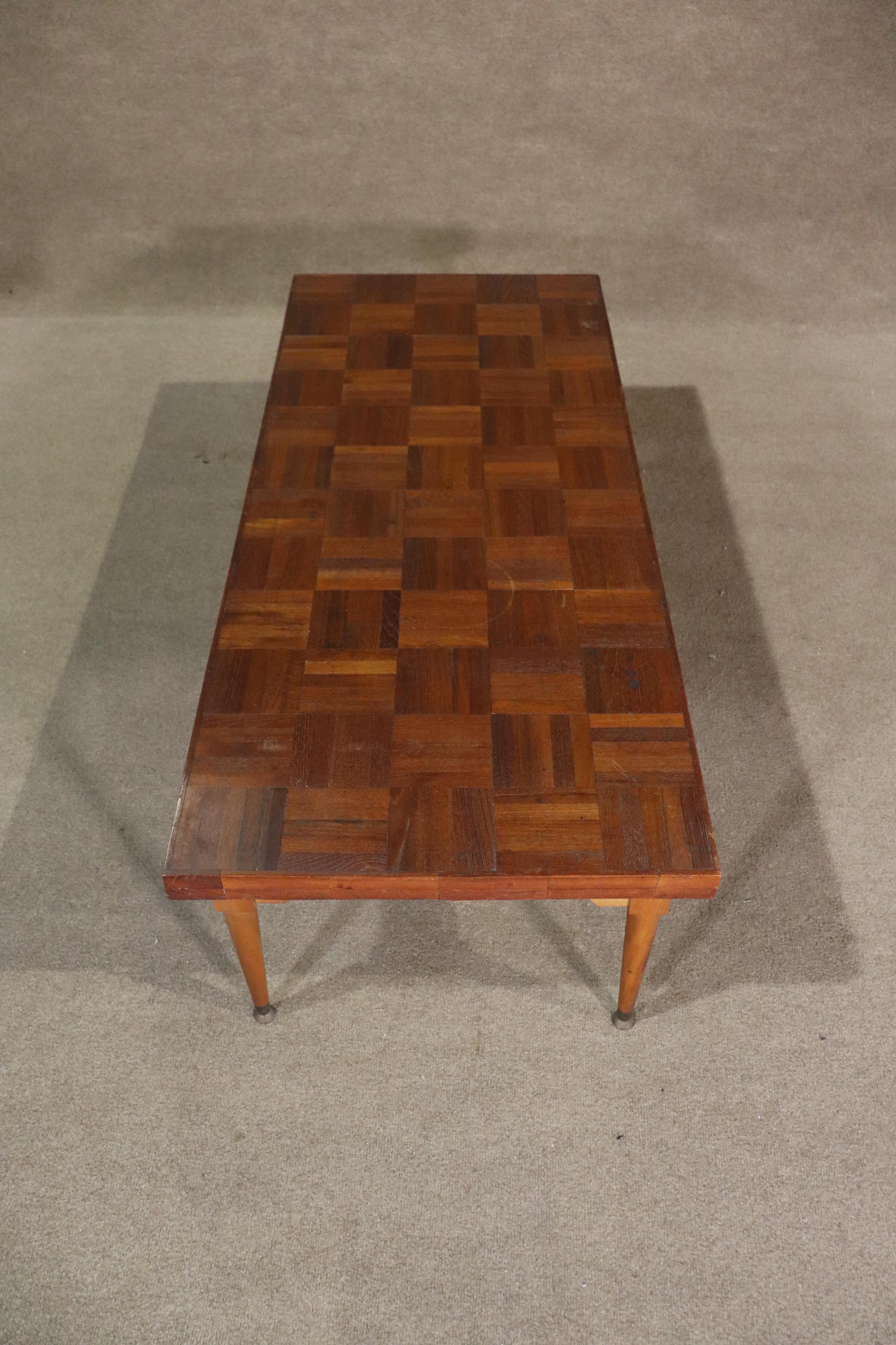 Longue table basse moderne du milieu du siècle avec un design en patchwork de lattes de teck. Elle repose sur des pieds fuselés en laiton.
Veuillez confirmer le lieu NY ou NJ