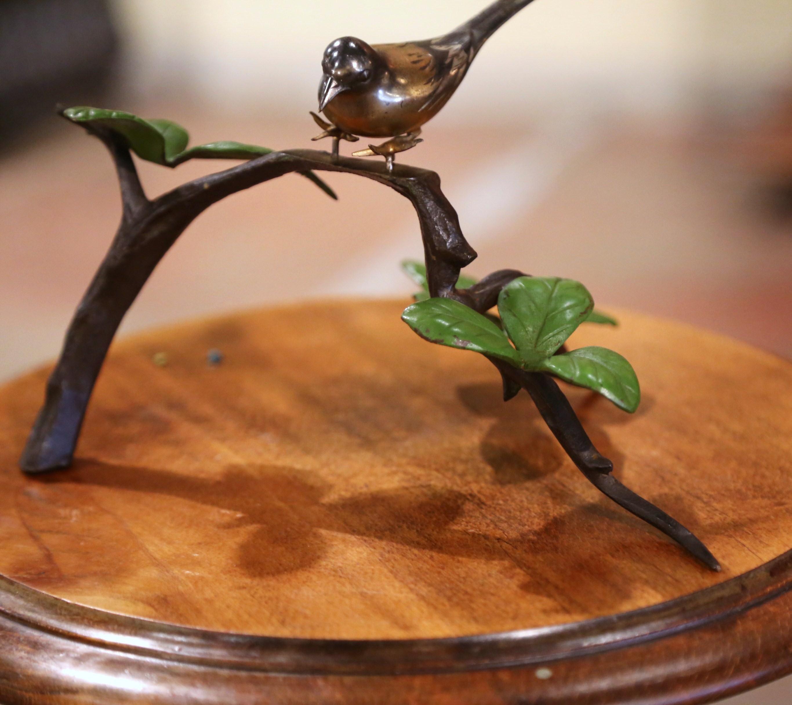This antique intricate bird on tree branch figure was created in France circa 1930.  The bronze sculpture features three leaflets each painted green with intricate details of the leaf veins. The bird exhibits elegant, detailed characteristics and a