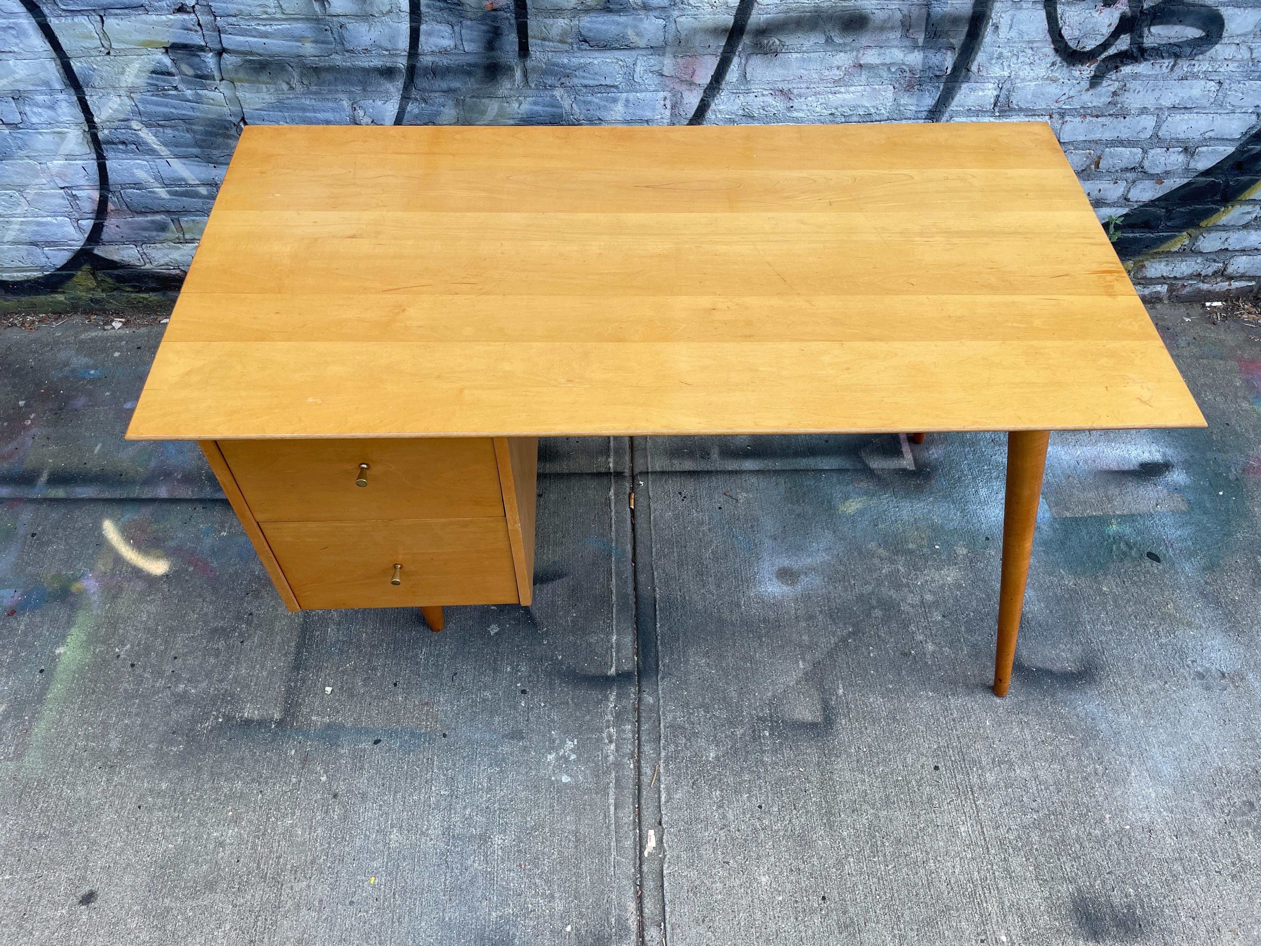 Bellissima scrivania a due cassetti Paul McCobb Group #1560 in acero biondo con pomelli in ottone a cono in acero massiccio. La scrivania è in buone condizioni vintage. Scrivania dal design molto bello con gambe affusolate, interamente in acero