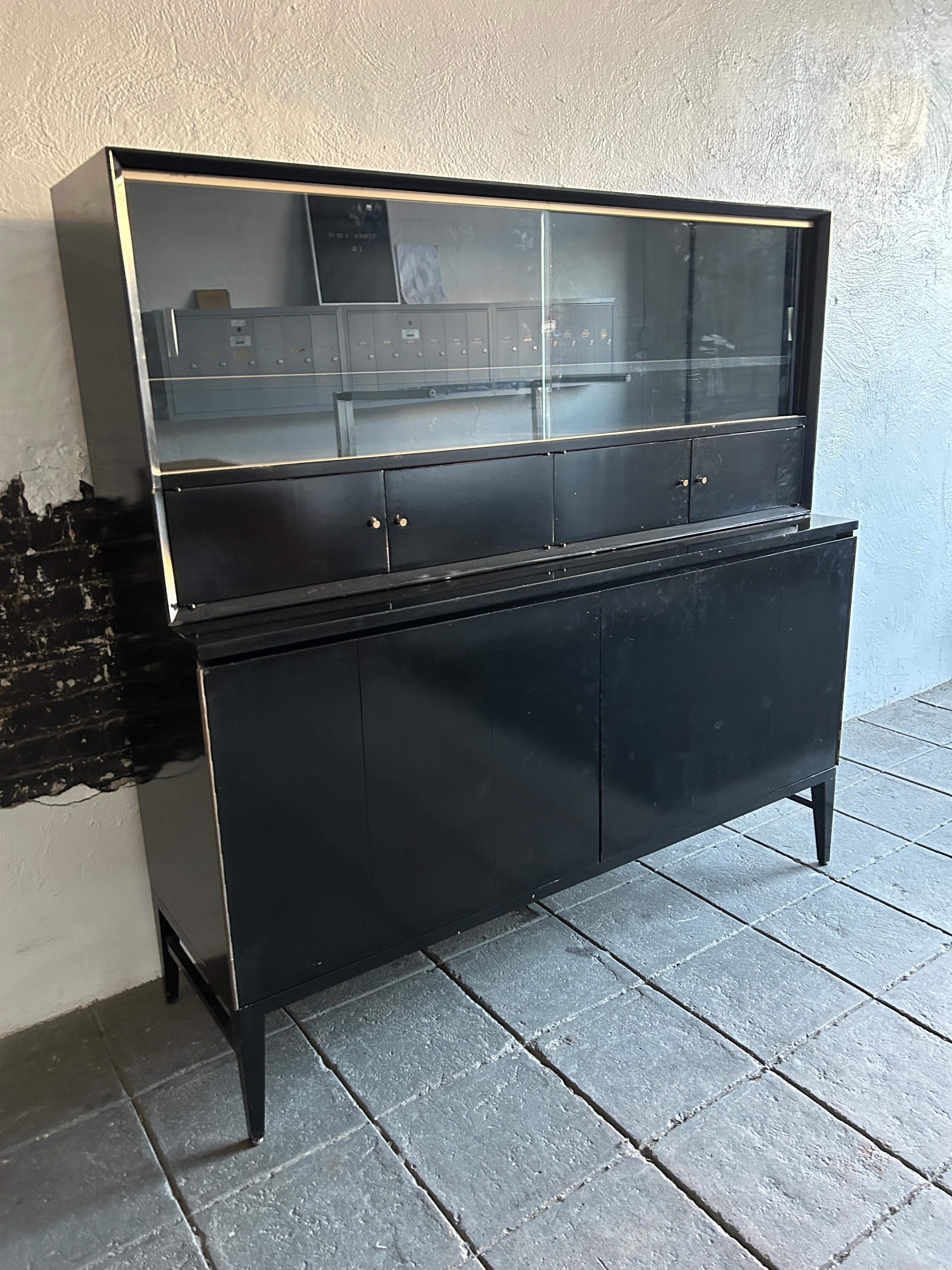 Mid century American designer Paul McCobb Calvin Irwin Collection credenza unit In Black Lacquer.  Has top unit with Glass doors and lower small storage areas. The lower Credenza has 2 sets of ffolding front doors. Has 4 drawers on Right and 1