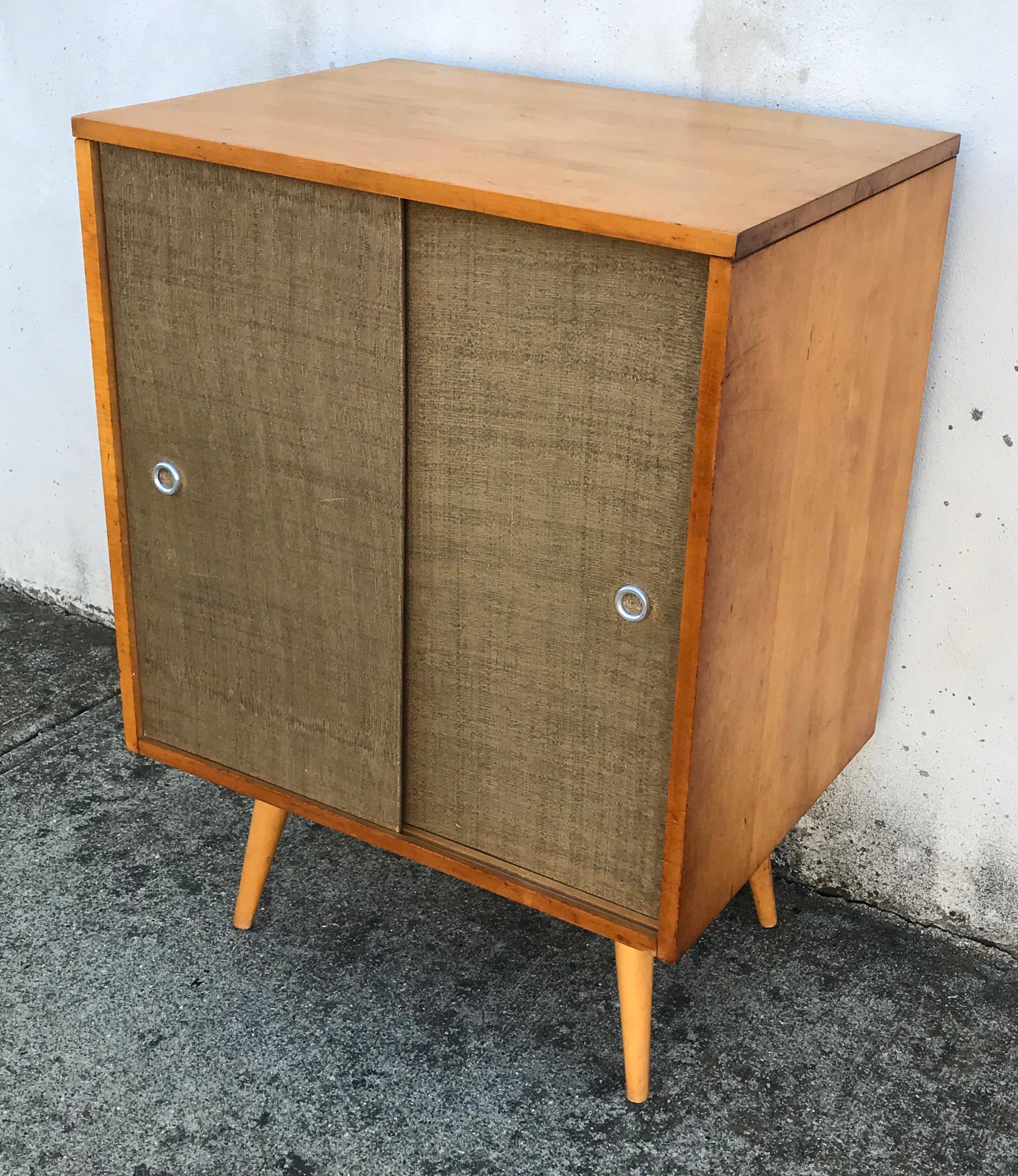 Nice small scale credenza cabinet by Paul McCobb for Planner Group, 1950s. Solid maple shell with original grass cloth sliders.
