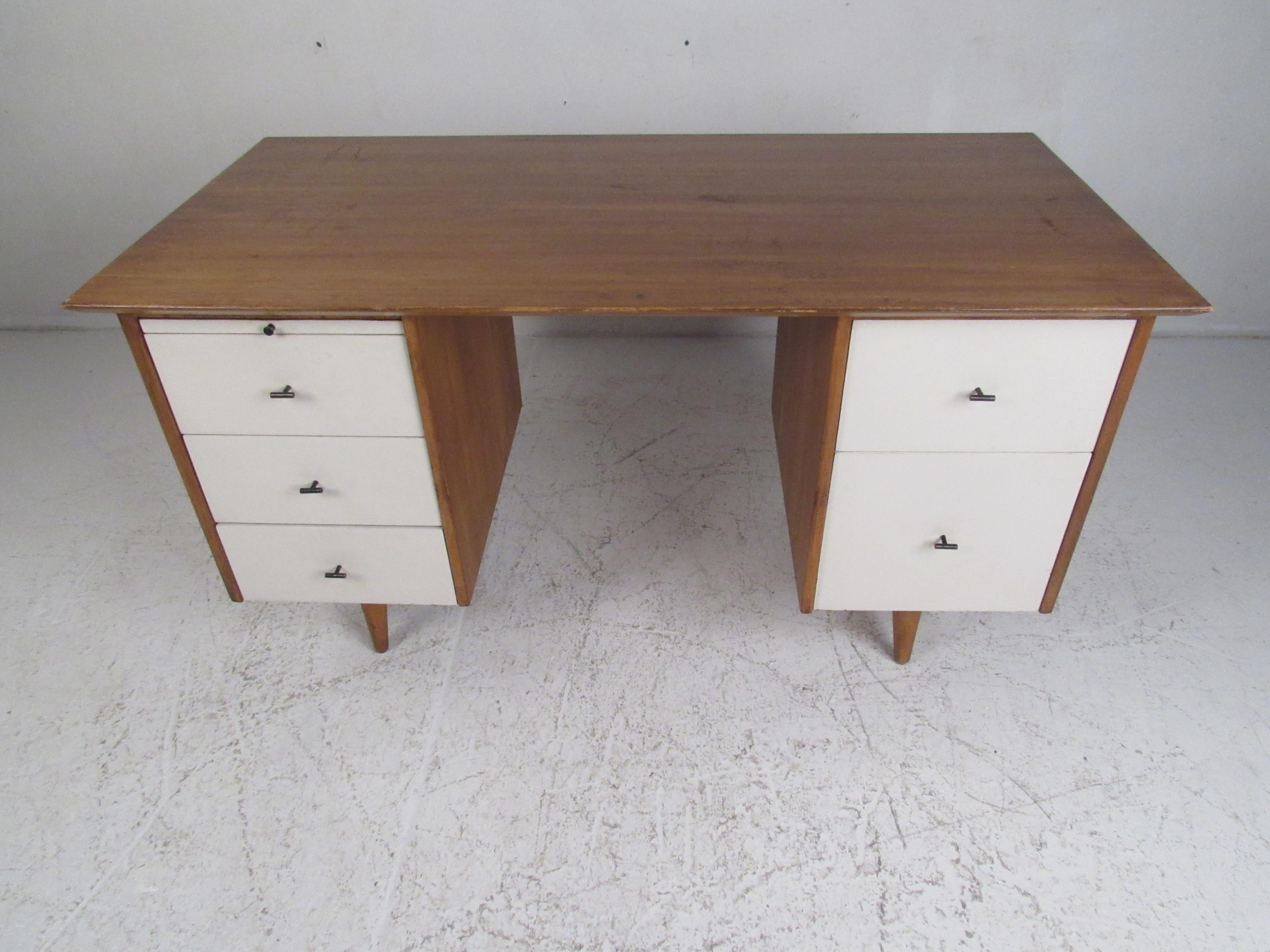 This stunning vintage modern desk boasts a large top ensuring plenty of workspace and five hefty drawers for ample storage. A unique design by Paul McCobb for planners group with white painted drawer fronts, unusual metal pulls, and tapered legs.