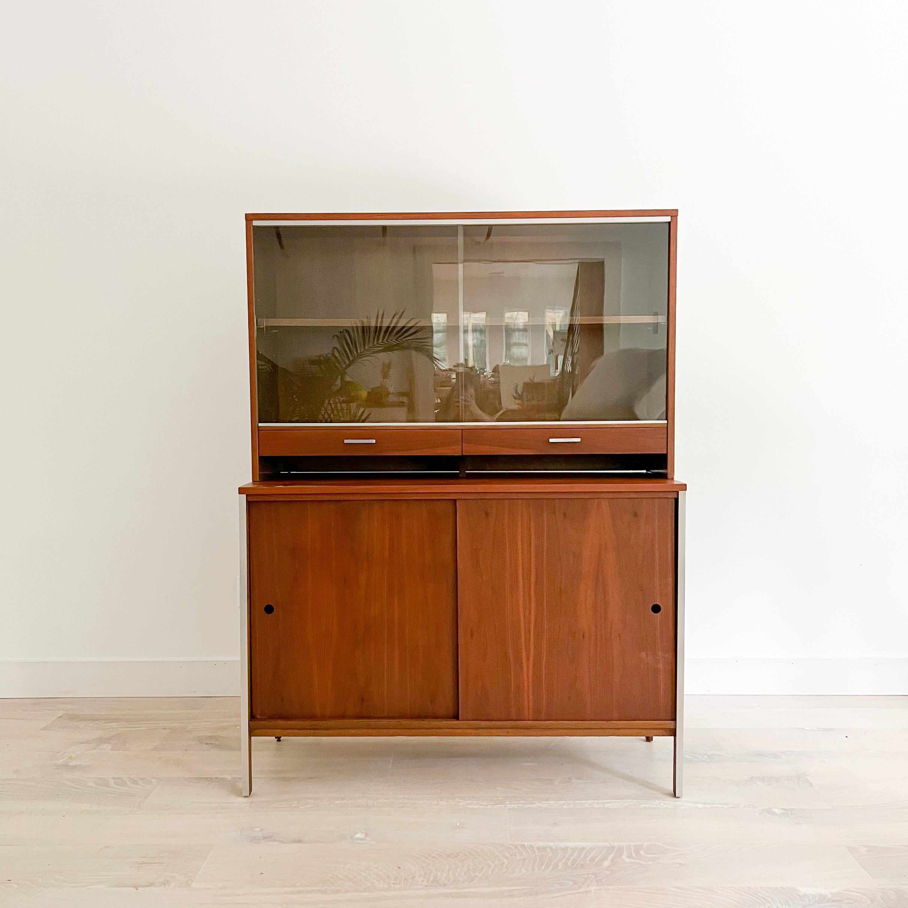 Mid-Century Modern two part walnut hutch designed by Paul McCobb for Calvin Furniture. Stamped on the inside of the top left drawer. The cabinet doors open up to adjustable shelving (which can accommodate vinyl). There is one small chip in the glass