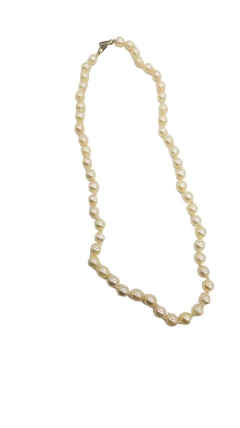 An emblem of mid-century grace, this dainty pearl choker is a refined statement. Delicate pearls, elegantly strung, evoke timeless sophistication. Accentuated by gold-plated embellishments, it exudes understated luxury. The sterling silver clasp