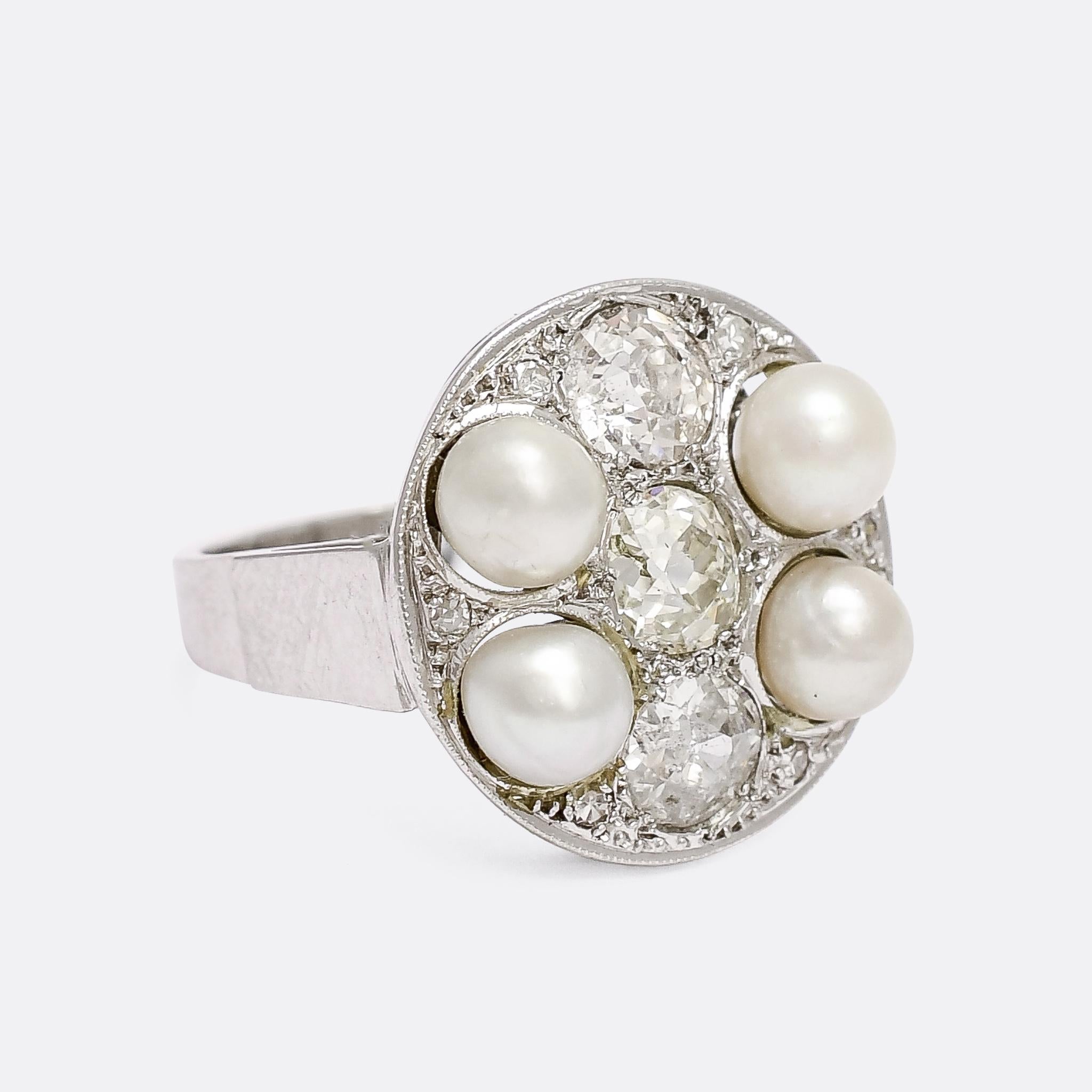 A spectacular mid-Century modern cocktail ring dating from the 1940s. It's set with seven primary stones: four natural pearls and three 3/4 carat old mine cut diamonds. The stones are set in finely millegrained platinum on a round, dish-like face,