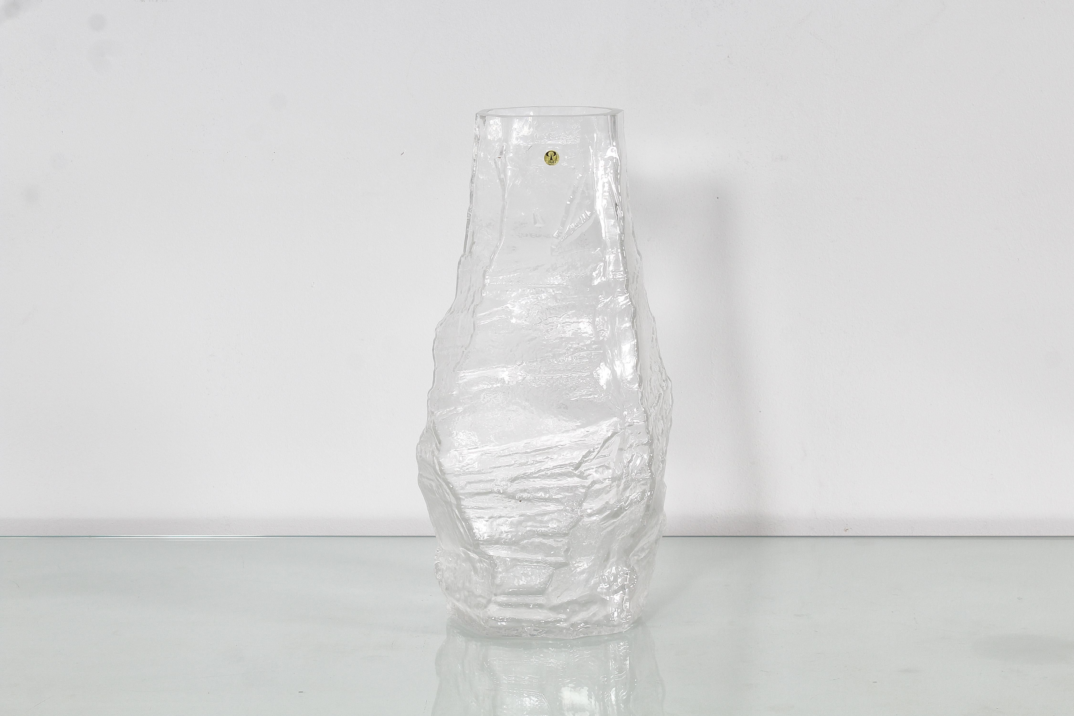 Beautiful and unusual thick and heavy 'glacier' clear glass vase, with an irregular shape, made by Peill & Putzler of Germany, in 1970s. Manufacturer's label near the edge. 
Wear consistent with age and use.