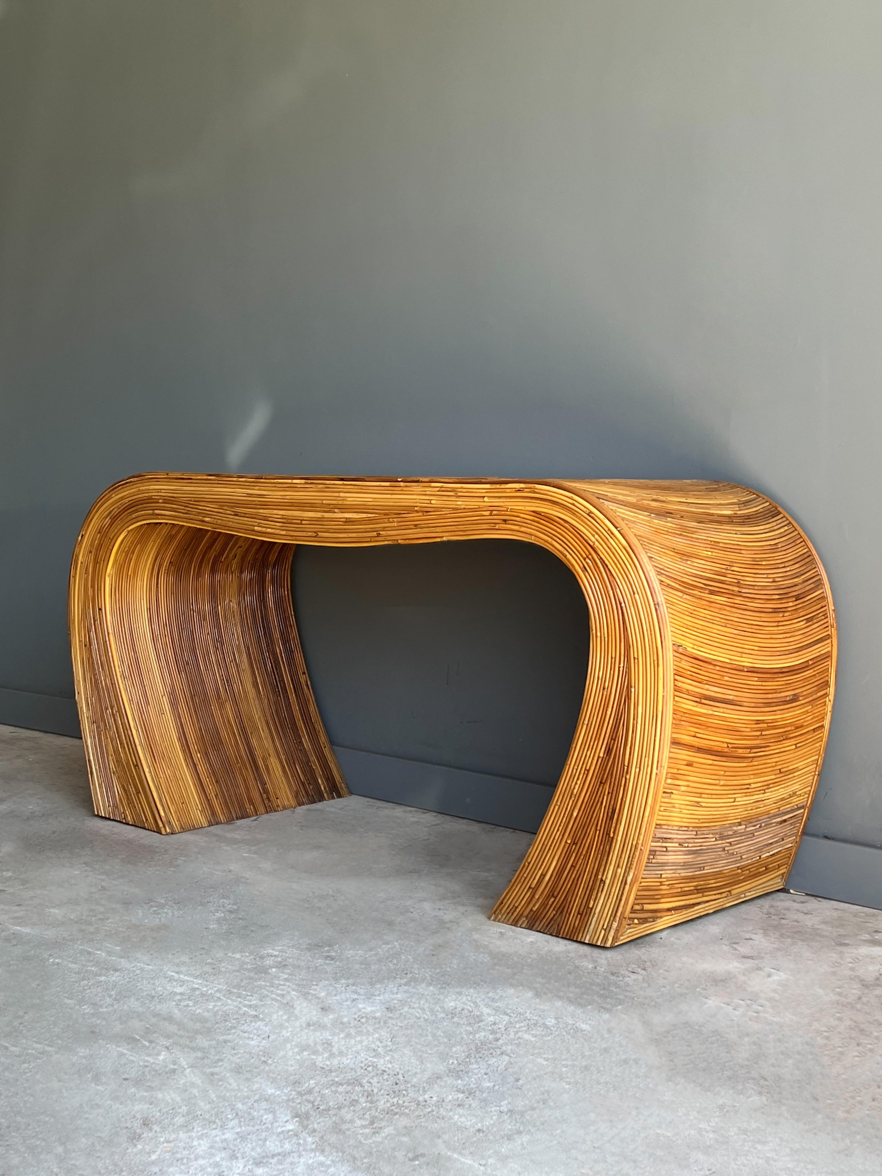 Vintage pencil reed console, circa 1960s. This beautiful console features an organic rounded shape with the attractive circular pattern on top. Lovely aged fluctuation of coloring. Patina all around. Some wear as shown. 

This sculptural table can