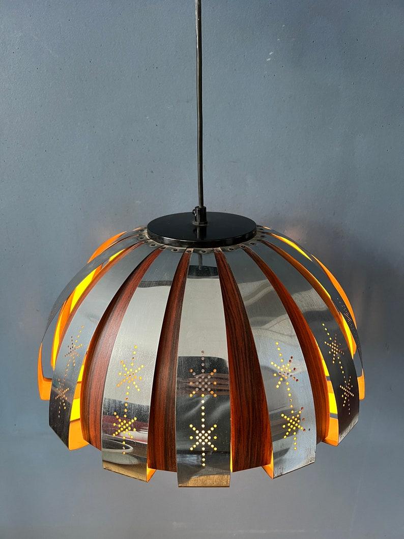 Ciondolo unico nel suo genere realizzato da Werner Schou per Coronell Elektro Danimarca. La luce si riflette magnificamente sulle parti cromate e in legno. La lampada richiede una lampadina E27/26 (standard).

Informazioni aggiuntive:
Materiali: