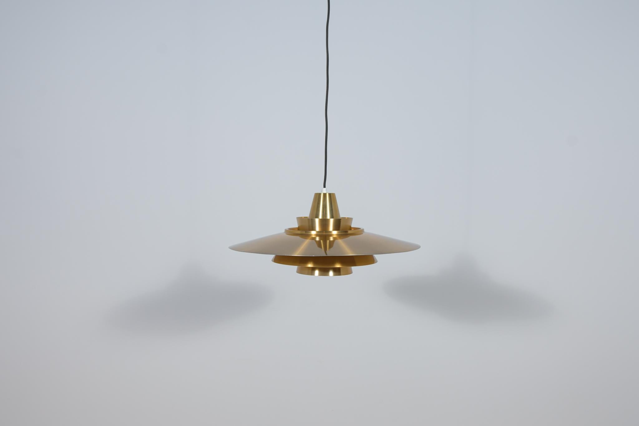 Pendant lamp made in Denmark in the 1970s. It is made of brushed aluminum in gold. The lamp is in very good condition with slight traces of use. The wiring has been replaced. The lamp has been checked by an electrician and is fully functional.