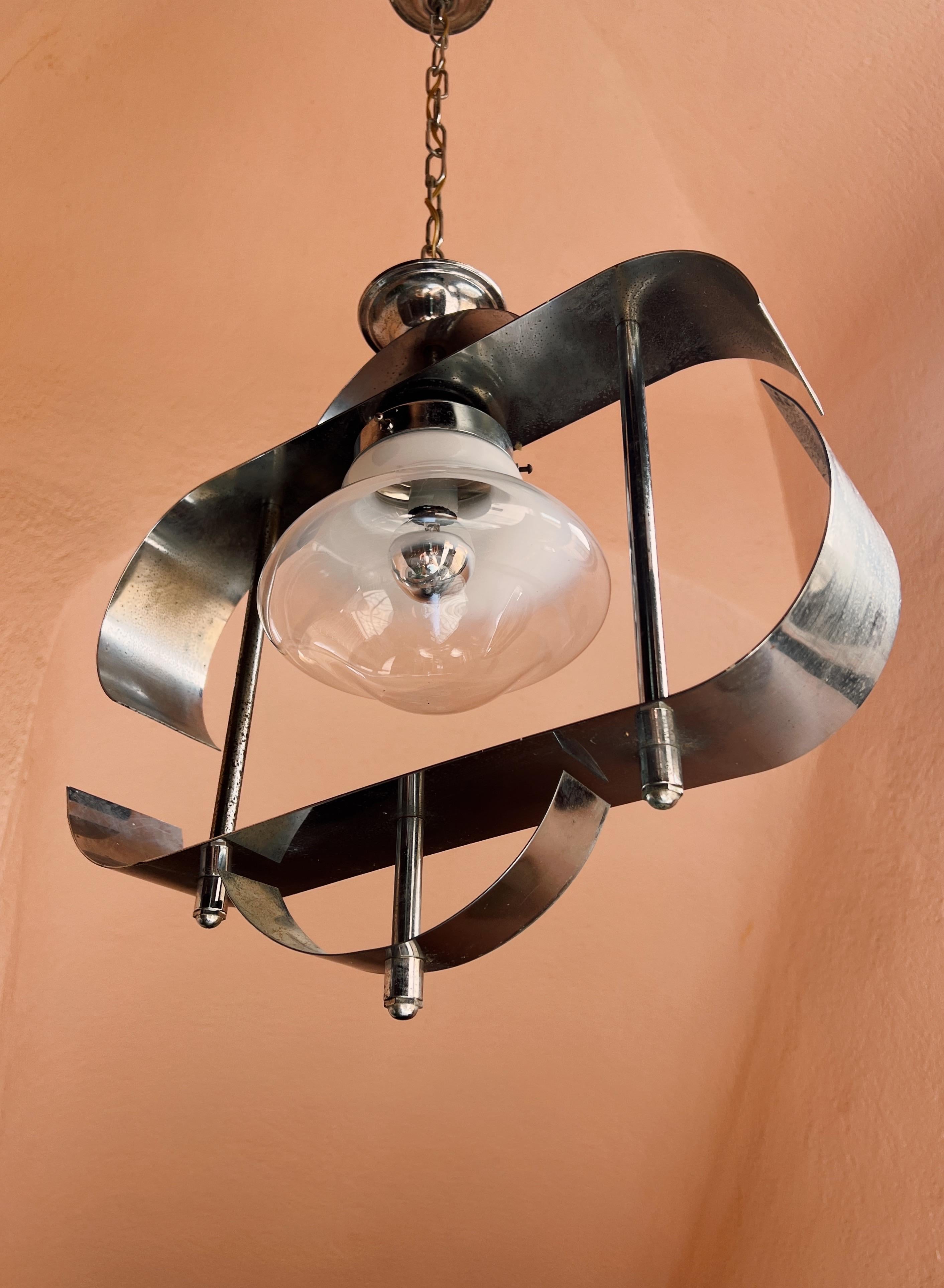 Lámpara colgante de mediados de siglo de Murano, Mazzega. La transición del cristal blanco opaco a un acabado transparente, crea un bello efecto cuando se ilumina. El globo de cristal está elegantemente encajado en una base de acero, con un diseño