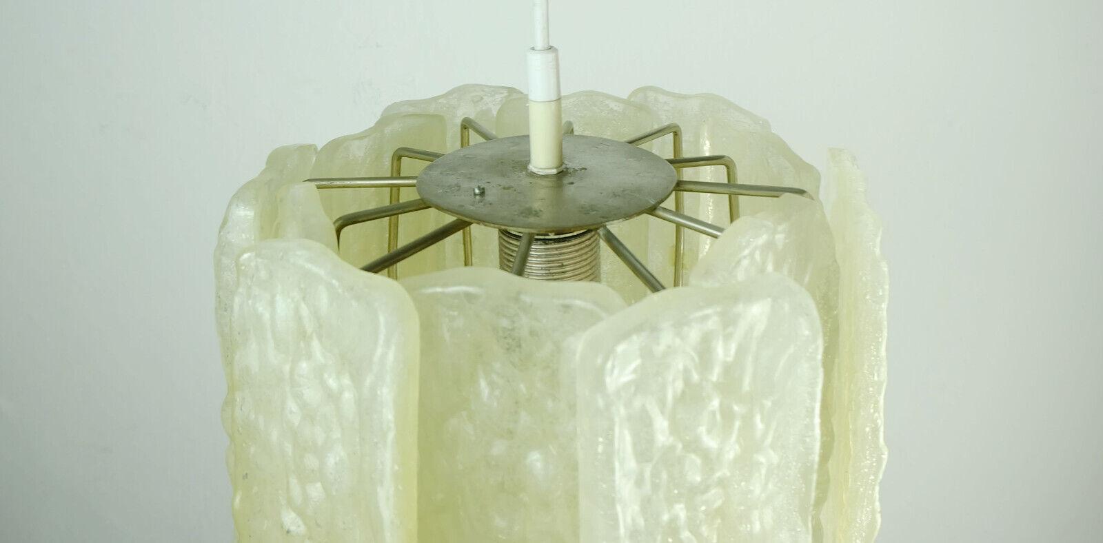 Lampe suspendue datant de la fin des années 1960 à 1970. Le cadre est en métal argenté. L'abat-jour se compose de 12 disques rectangulaires en acrylique avec un aspect de verre glacé qui sont fixés aux tiges de support. Au milieu se trouve une