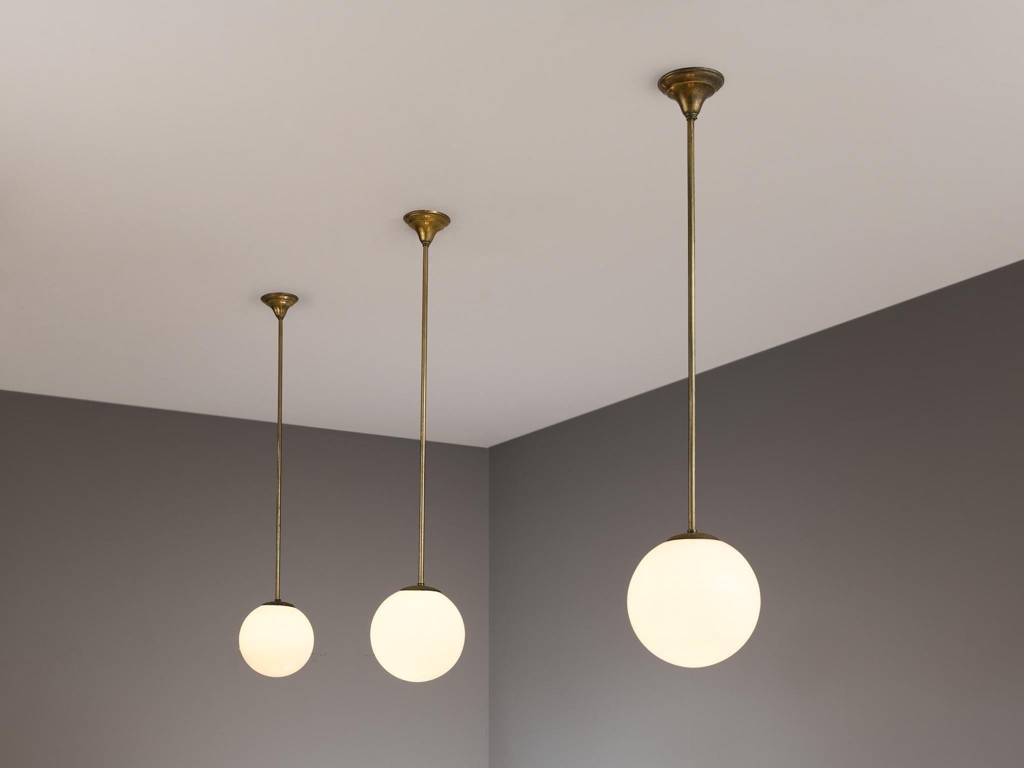 Pendants, opaline glass, Europe, 1960s.

These atmospheric pendant lamps features each an opaline glass orb. This results in a nice and soft light-tone creating a lively ambience in the room. The sphere is suspended by an elongated brass fixture.