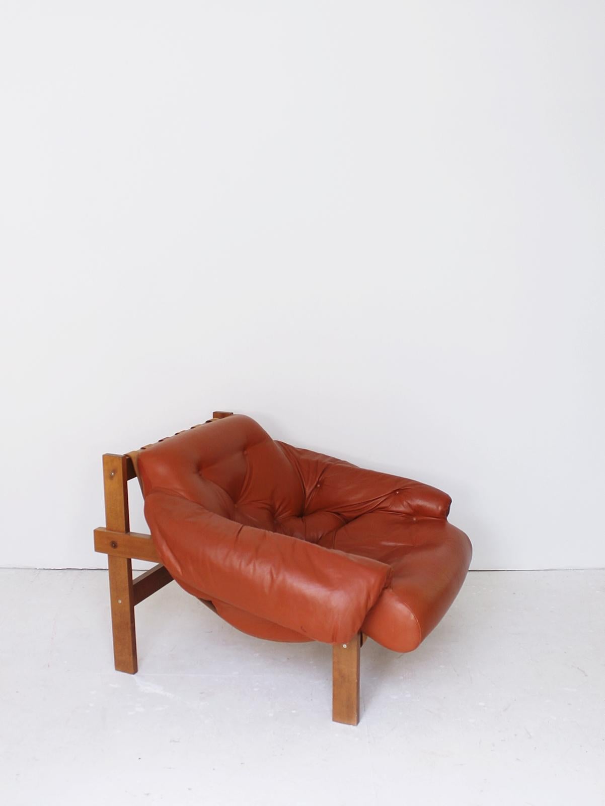 Stunning  leather armchair in manner of Brazilian designer Percival Lafer. 
Featuring a solid wood frame with beautiful grain that supports the natural leather straps which the tufted  leather cushion rests on. 
The original leather upholstery in