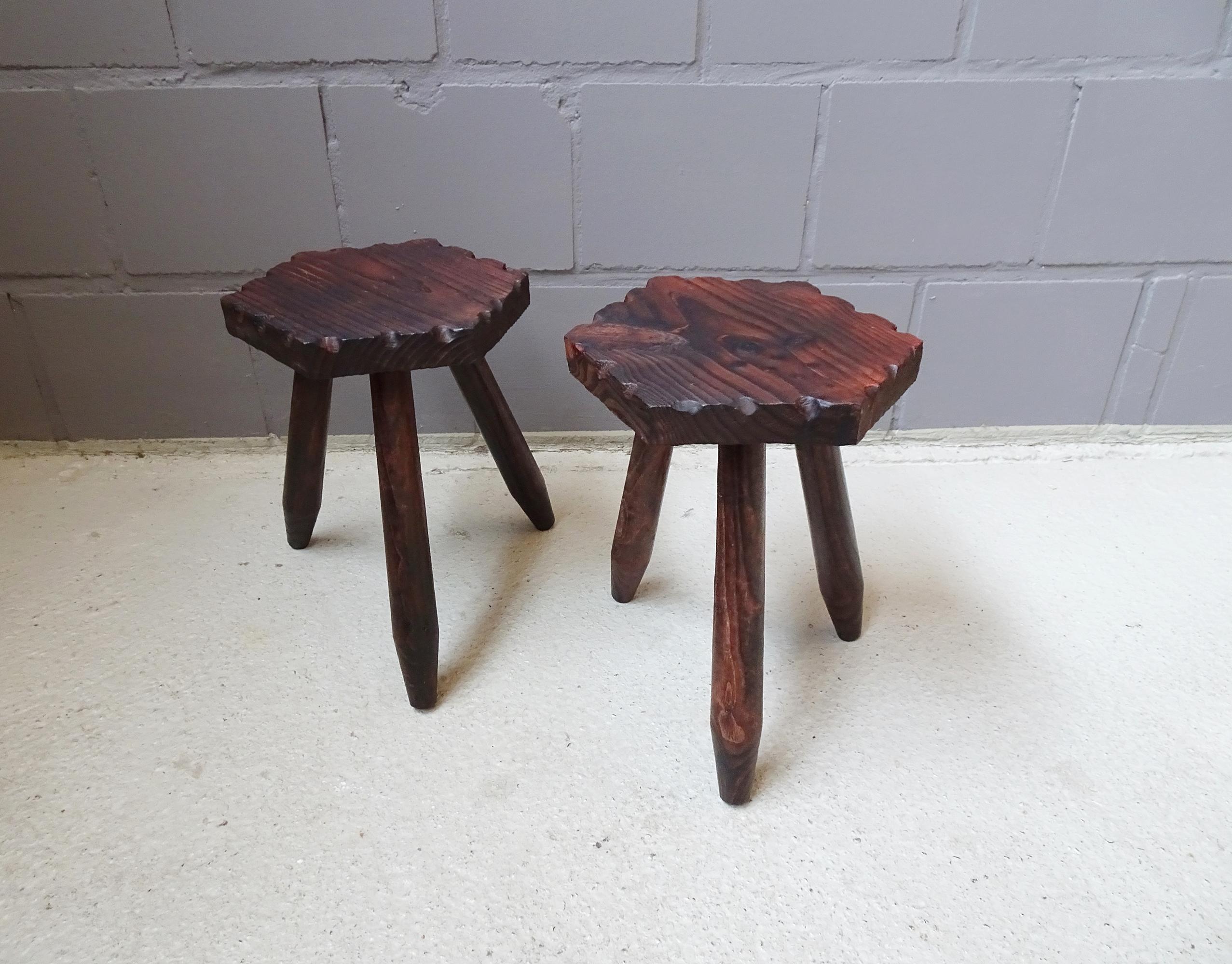 Set of two rustic wooden tripod stools. Hexagonal seat with slight notches and three flared legs. The solid, dark oiled wood enhances the rustic look.

Two handcrafted tripod stools, simple and natural, can be easily combined with modern