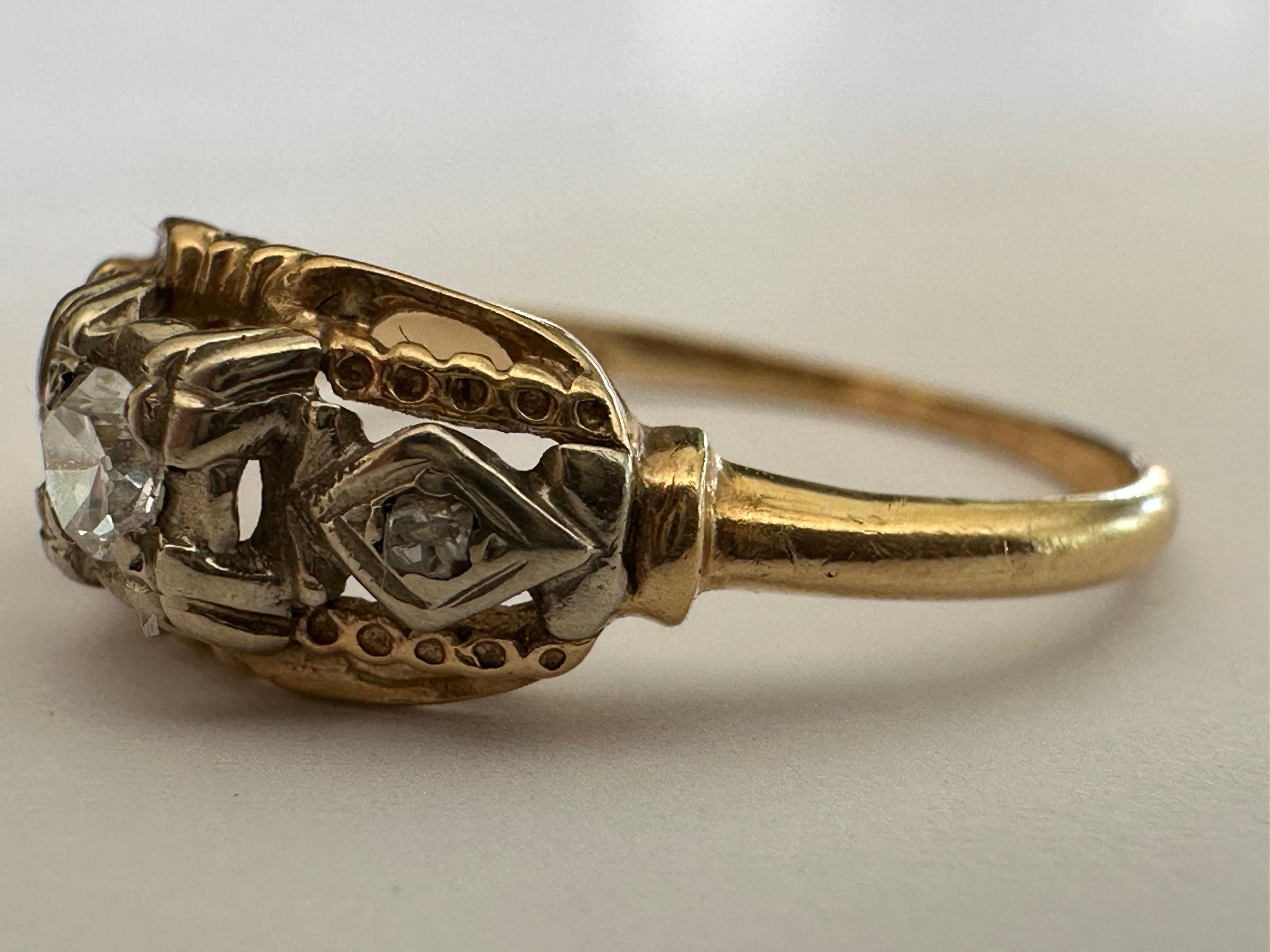 An Old European-cut diamond measuring approximately 0.08 carat, G color VS clarity, centers this mid-century ring accented by a pair of single cut diamonds atop a hand engraved, openwork mounting set in 14K yellow gold. The maker's mark indicates it