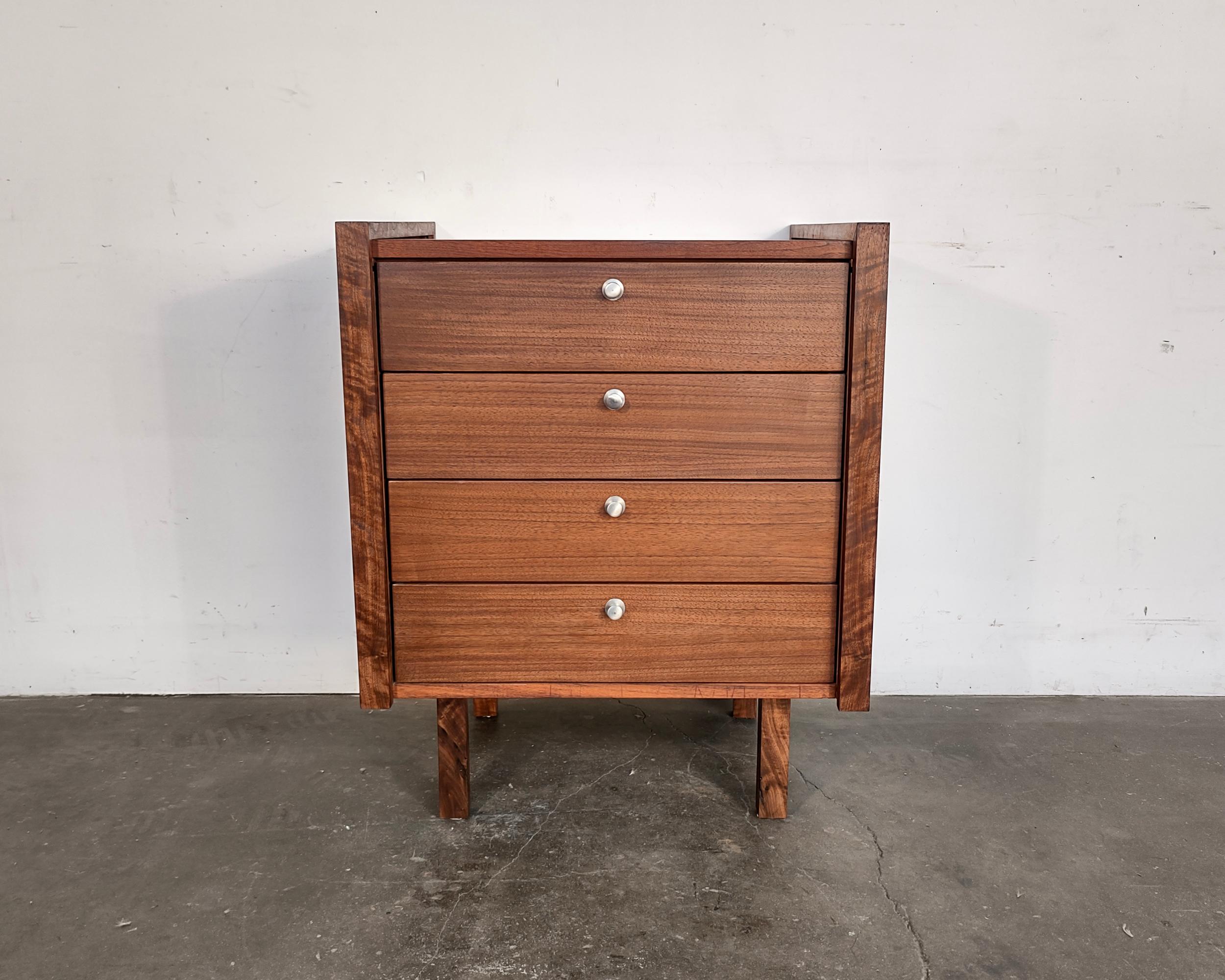 Professionally restored walnut chest of drawers designed by Martin Borenstein for Brown Saltman, circa 1960. Gorgeous walnut wood grain covering entire body with solid wood border details + legs. Four drawers with original aluminum hardware and