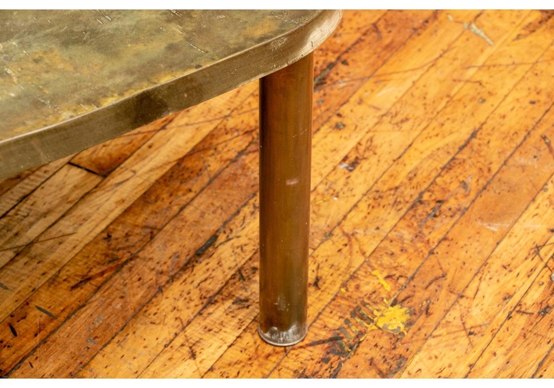 Classic midcentury cocktail table in acid etched patinated bronze, this one in an understated and undecorated mottled finish which is timeworn with signs of age. A square table with curved sides, raised on cylindrical legs. Signature etched on the