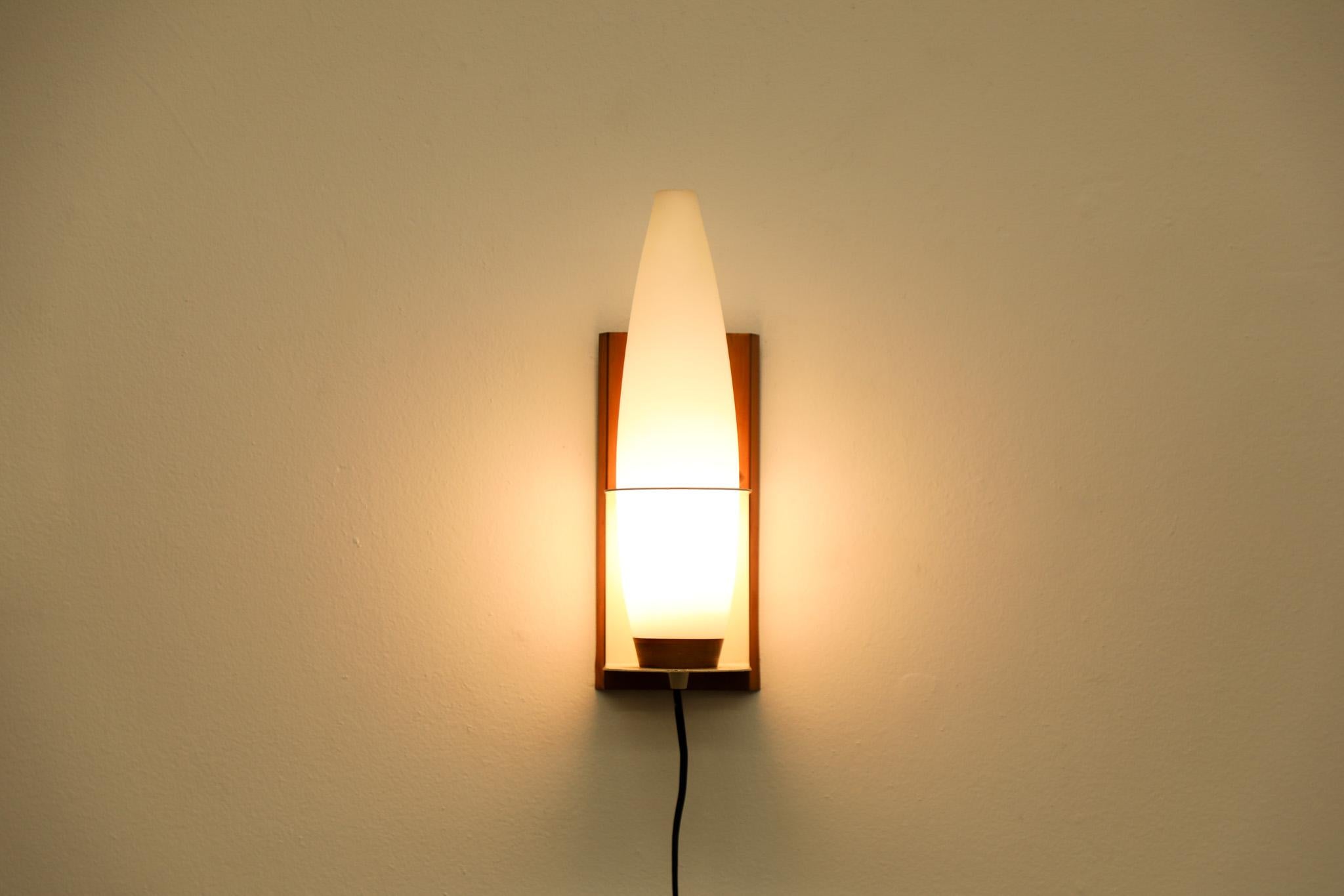 Mid-Century Philips wall sconce with natural teak frame, milk glass shade and white enameled metal hardware. Attributed to Louis Kalff, head designer for the Dutch company. An attractive wall lamp providing a balanced ambient light.  In overall