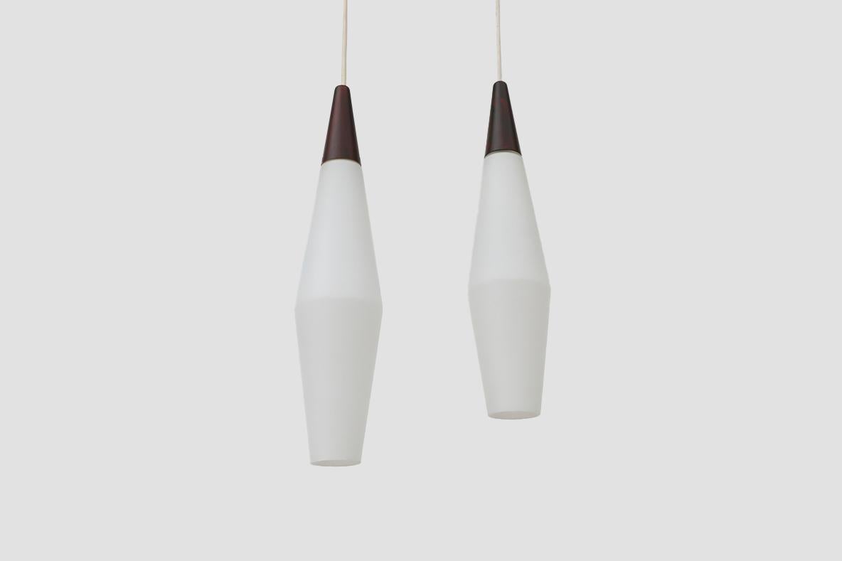 Mid-Century Philips frosted opaline milk glass pendant lights with faux rosewood tops and conical diamond shape. In original condition with visible wear consistent with their age and use.