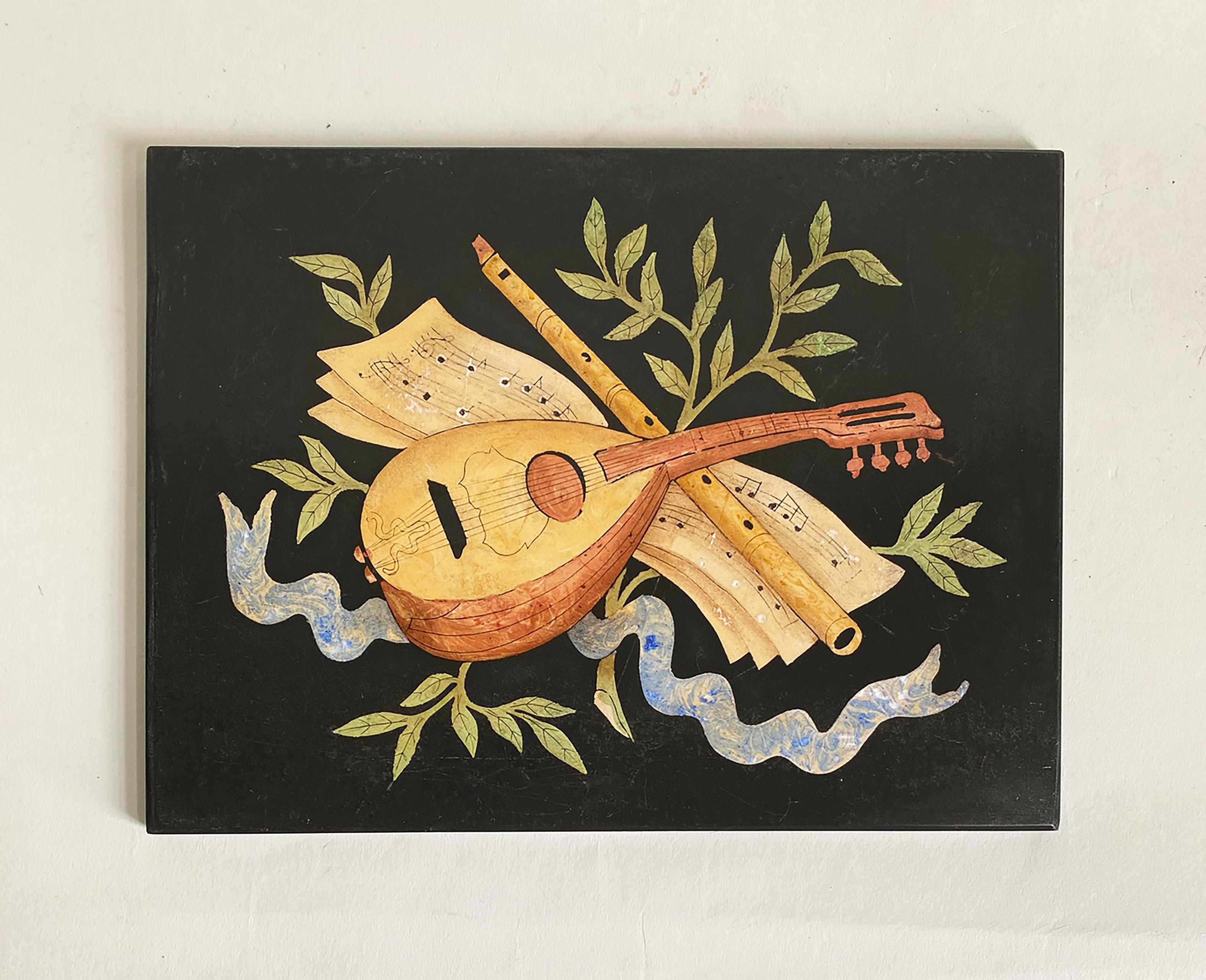 Here is a very decorative Italian Pietra Dura wall plaque which we're estimating, based on the motifs, is from the 1940s. It depicts a flute and a string instrument along with sheet music surrounded by branches and ribbon. The back of the plaque has