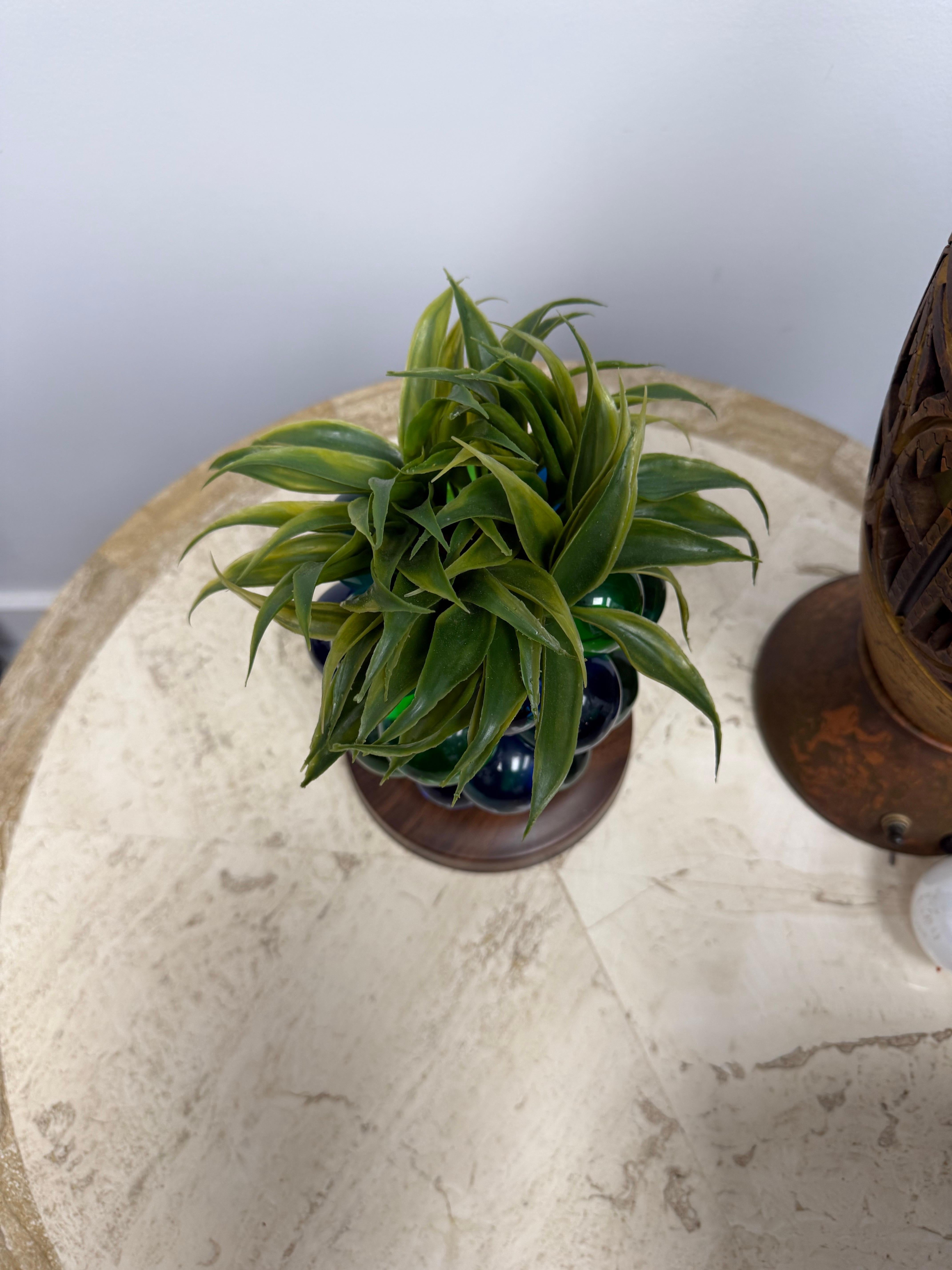 Eine lebendige, dekorative Traubenskulptur aus der Mitte des Jahrhunderts, gefertigt aus farbigen Lucite-Kugeln in Smaragdgrün und Kobaltblau. Das Arrangement ruht auf einem runden Holzsockel und ist mit künstlichem Grün bestückt, wodurch ein