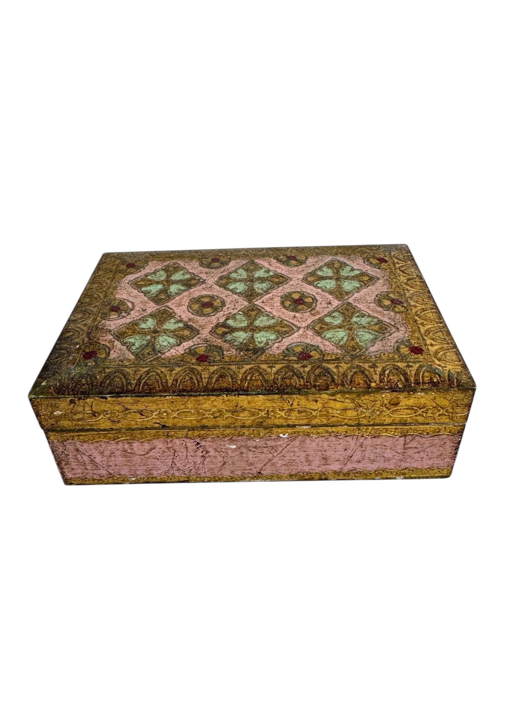 Charmante boîte Florentine en rose tendre avec un décor doré, fabriquée en Italie au milieu du 20e siècle. La surface peinte à la main présente des motifs dorés en volutes dans le style traditionnel de Florentine, mis en valeur par une patine