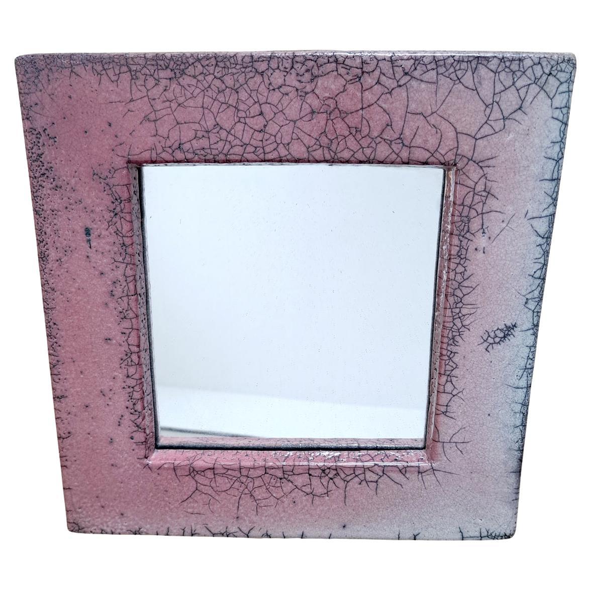 Charmant miroir mural en céramique du milieu du siècle, doté d'un cadre émaillé rose saisissant dans des tons riches de framboise et de blush doux avec des accents noirs subtils. La finition émaillée en couches donne de la profondeur et de la
