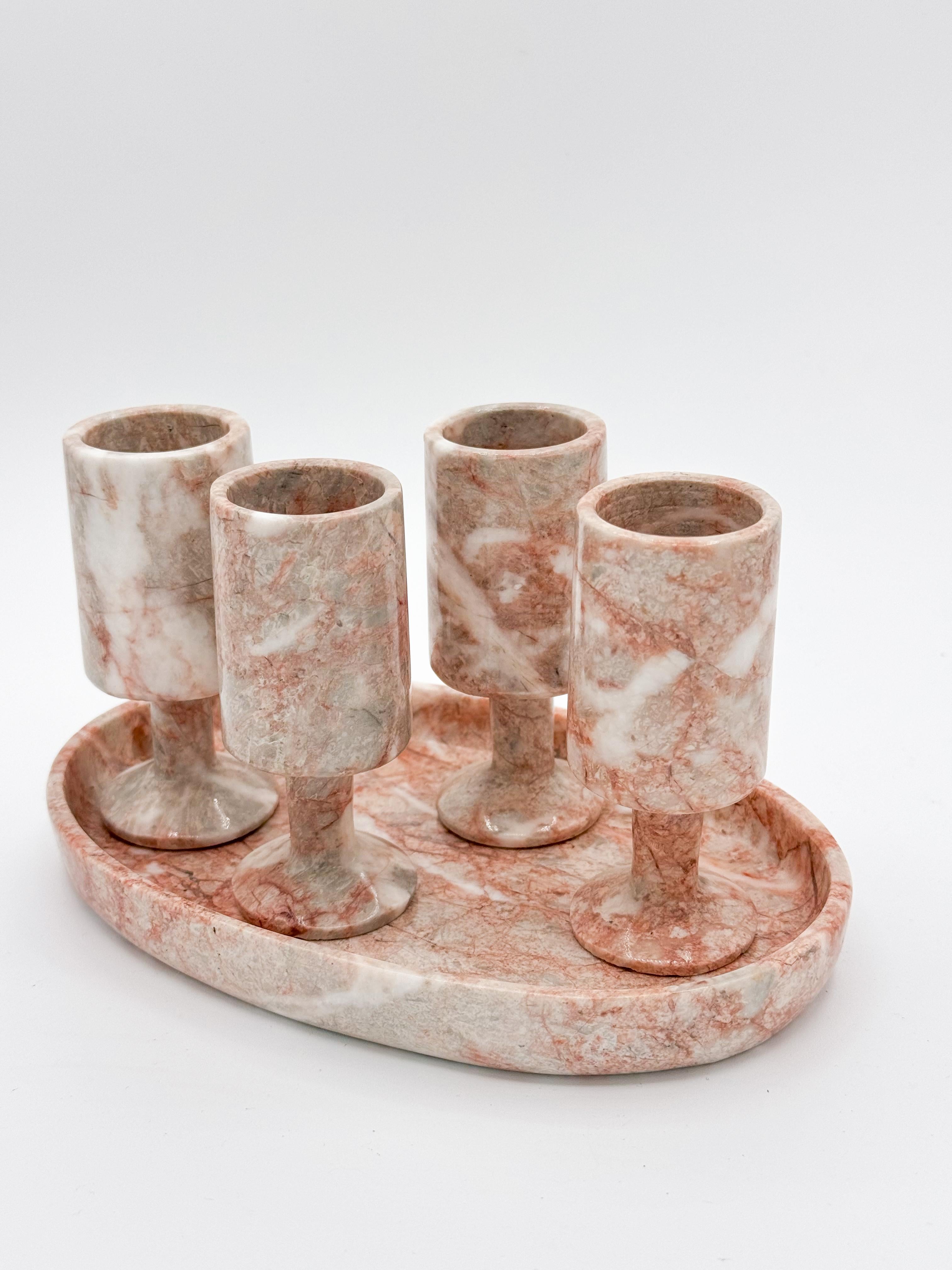 Verleihen Sie Ihrer Bar einen Hauch von zeitloser Eleganz mit diesem besonderen Mid Century Pink Marble Barware Set. 
Mit 4 wunderschön gearbeiteten Marmor-Shotgläsern und einem passenden Tablett verbindet dieses Set Funktionalität mit