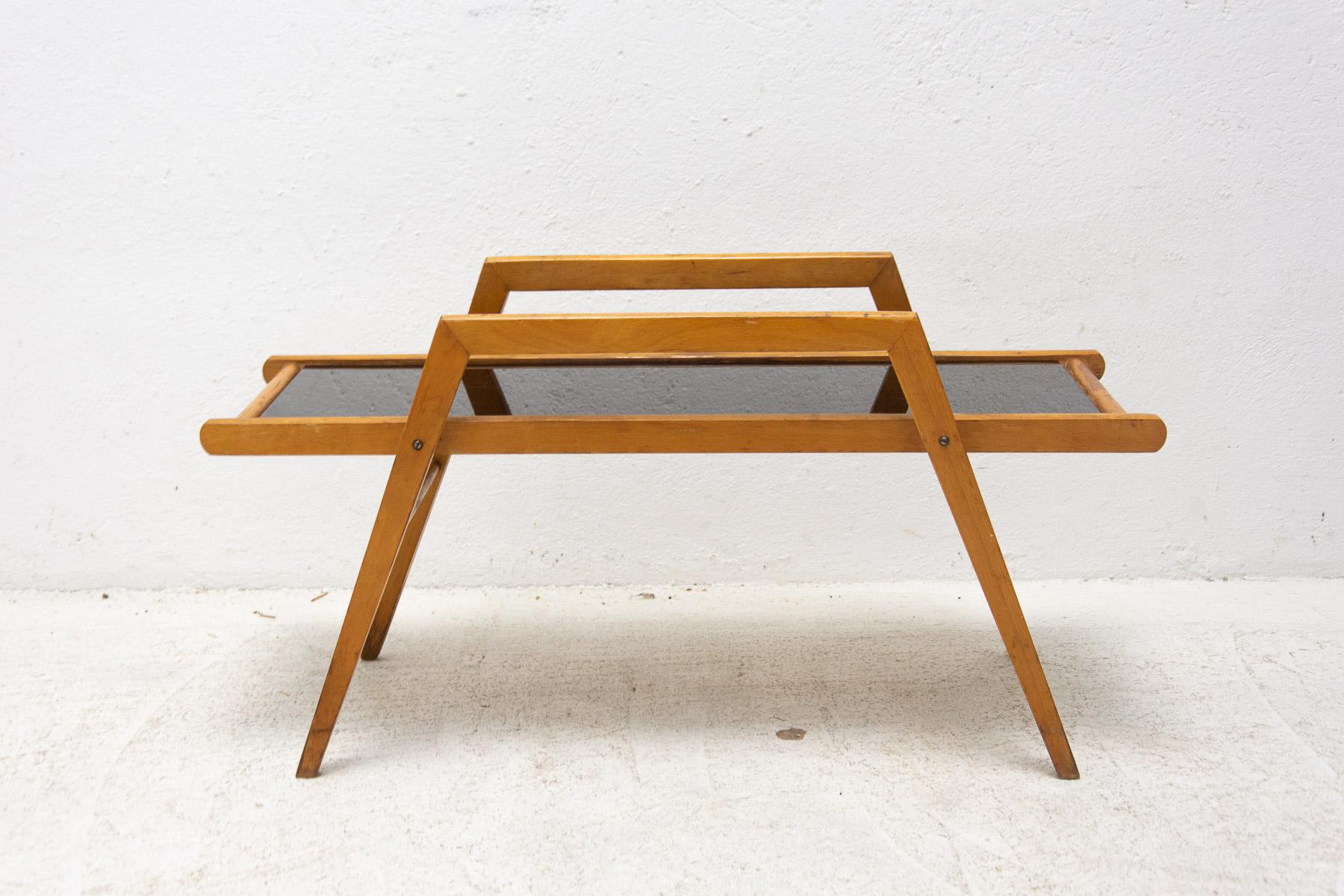 Mid-century plant stand, made in the former Czechoslovakia in the 1970's.

This table can be used as a plant stand or a side table. It's made of beech wood with woven leather straps and black glass. In good Vintage condition, shows signs of age