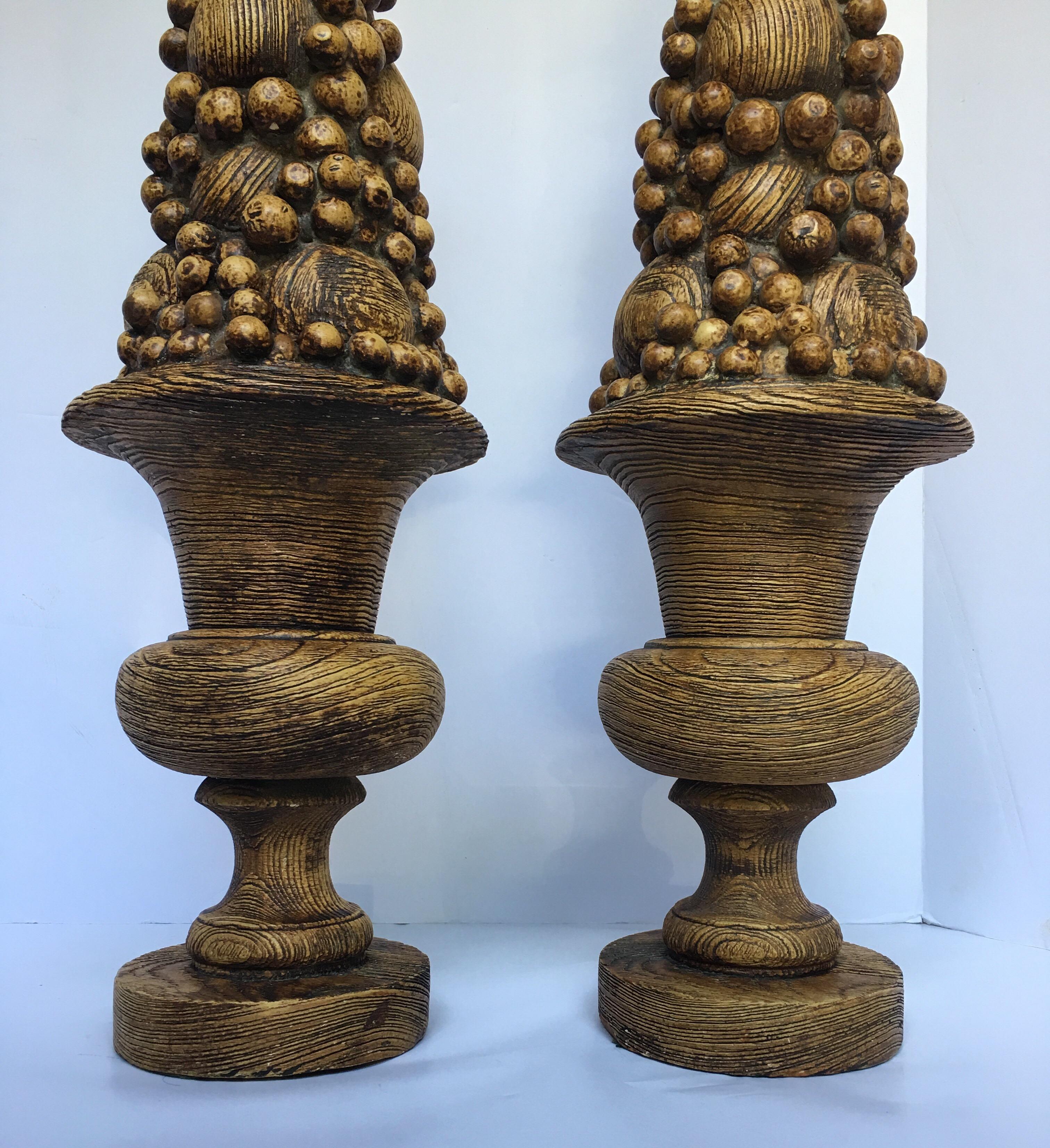 Pair of midcentury faux bois wood grain fruit topiary urns. These sculptural wood grain textured pieces are constructed of a heavy plaster. These tall obelisk form sculptures were once electrified table lamps and have been converted into decorative