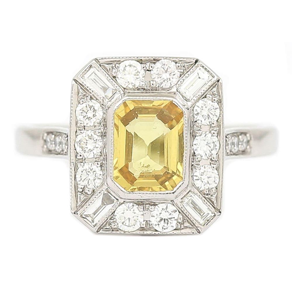 A lovely vintage mid-century platinum, yellow sapphire and diamond cluster ring. The rectangular step cut yellow sapphire is estimated at 1.21ct, there are a combination of both brilliant cut and baguette diamonds surrounding the sapphire which are