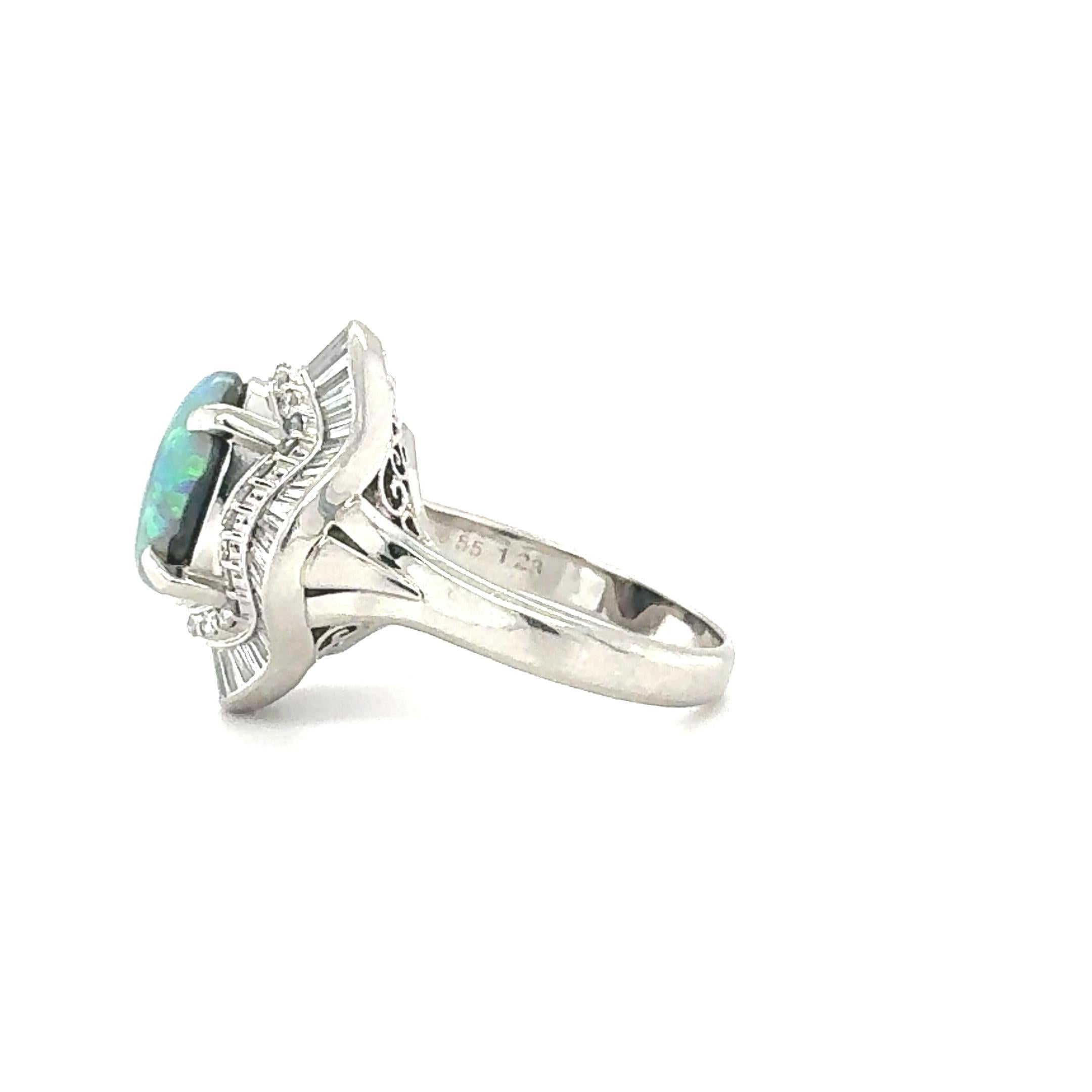 Questo squisito anello in stile ballerina degli anni '50 è un esempio di eleganza e maestria senza tempo. Realizzato in platino e timbrato PT900, il design è incentrato su un affascinante opale nero ovale cabochon da 2,55 carati, che misura 12,30 x